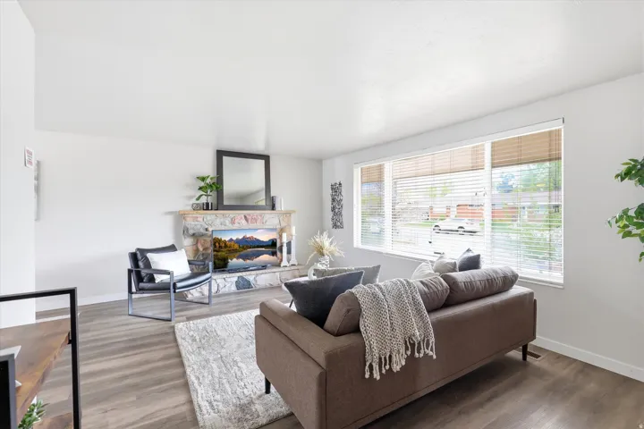 Wood-finish flooring, stone fireplace with mantel, and large picture windows