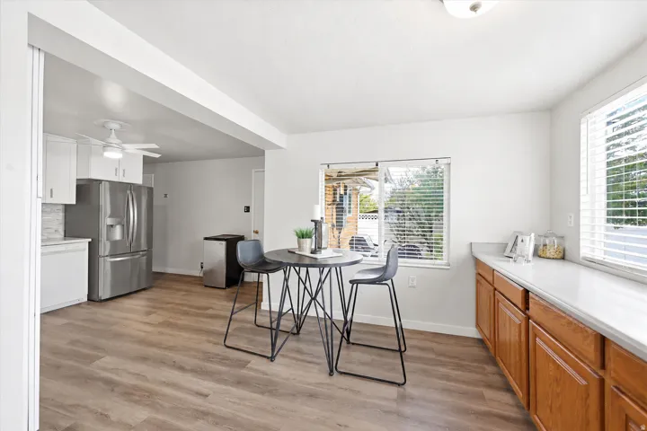 Kitchen featuring wood-finish flooring, white cabinetry, a tile backsplash, stainless steel appliances, and a window with blinds