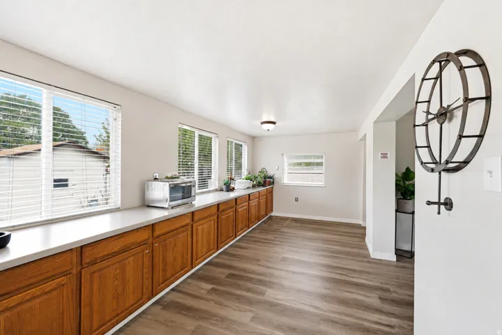 Wood-finish flooring, recessed lighting, and extensive wood cabinetry with light-toned countertops