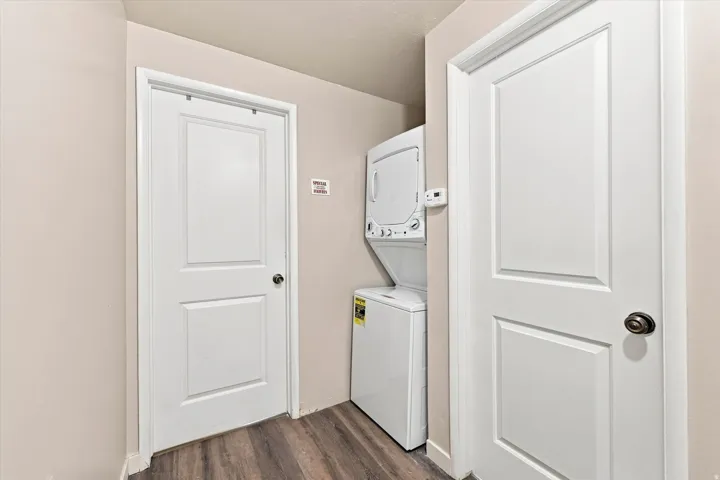 Main floor stackable laundry appliances with wood-finish flooring and two panel doors
