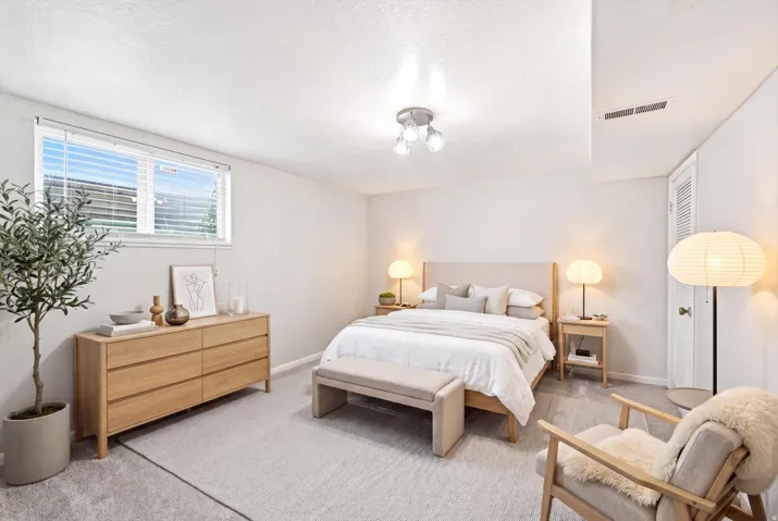 Basement bedroom featuring a window with blinds,and a built-in closet with louvered doors