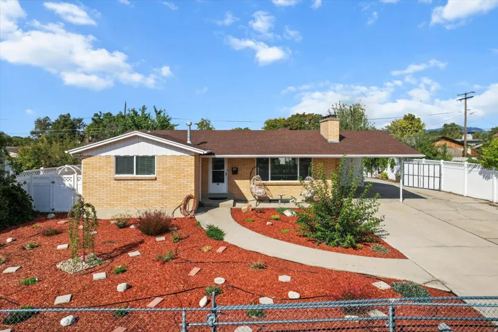 Brick exterior with a brown shingle roof, a paved driveway, and a white carport