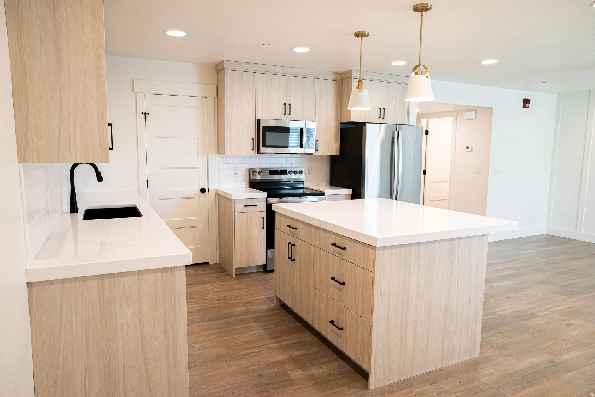 Modern kitchen featuring wood-finish cabinetry, stainless steel appliances, and white countertops