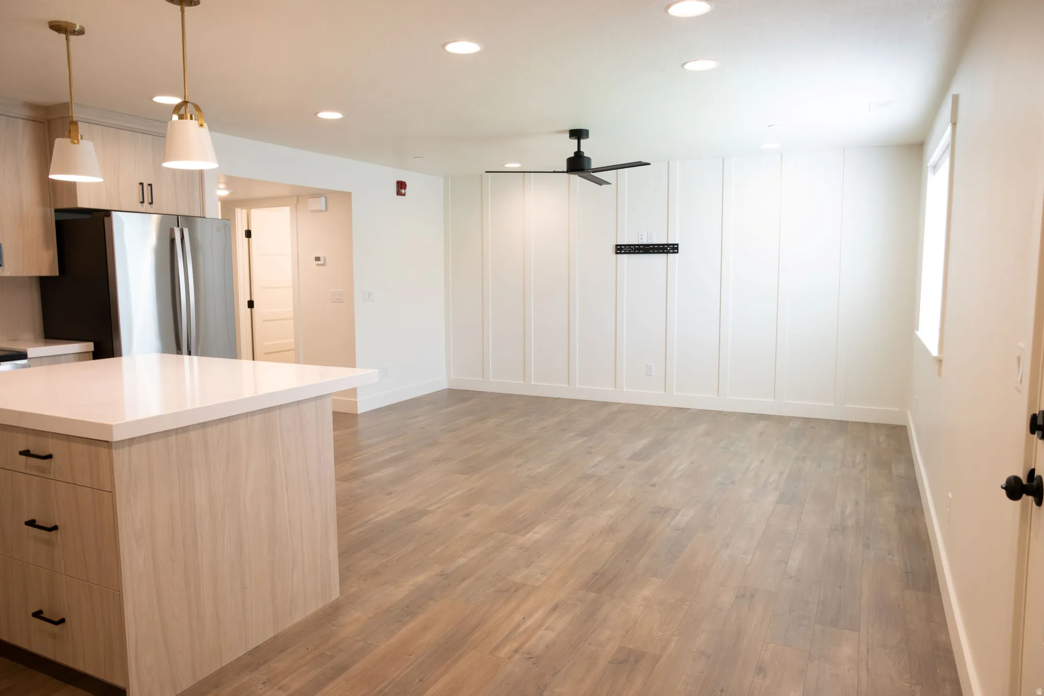 Open-concept living space featuring wood-finish flooring, recessed lighting, and a kitchen island with a light-toned countertop