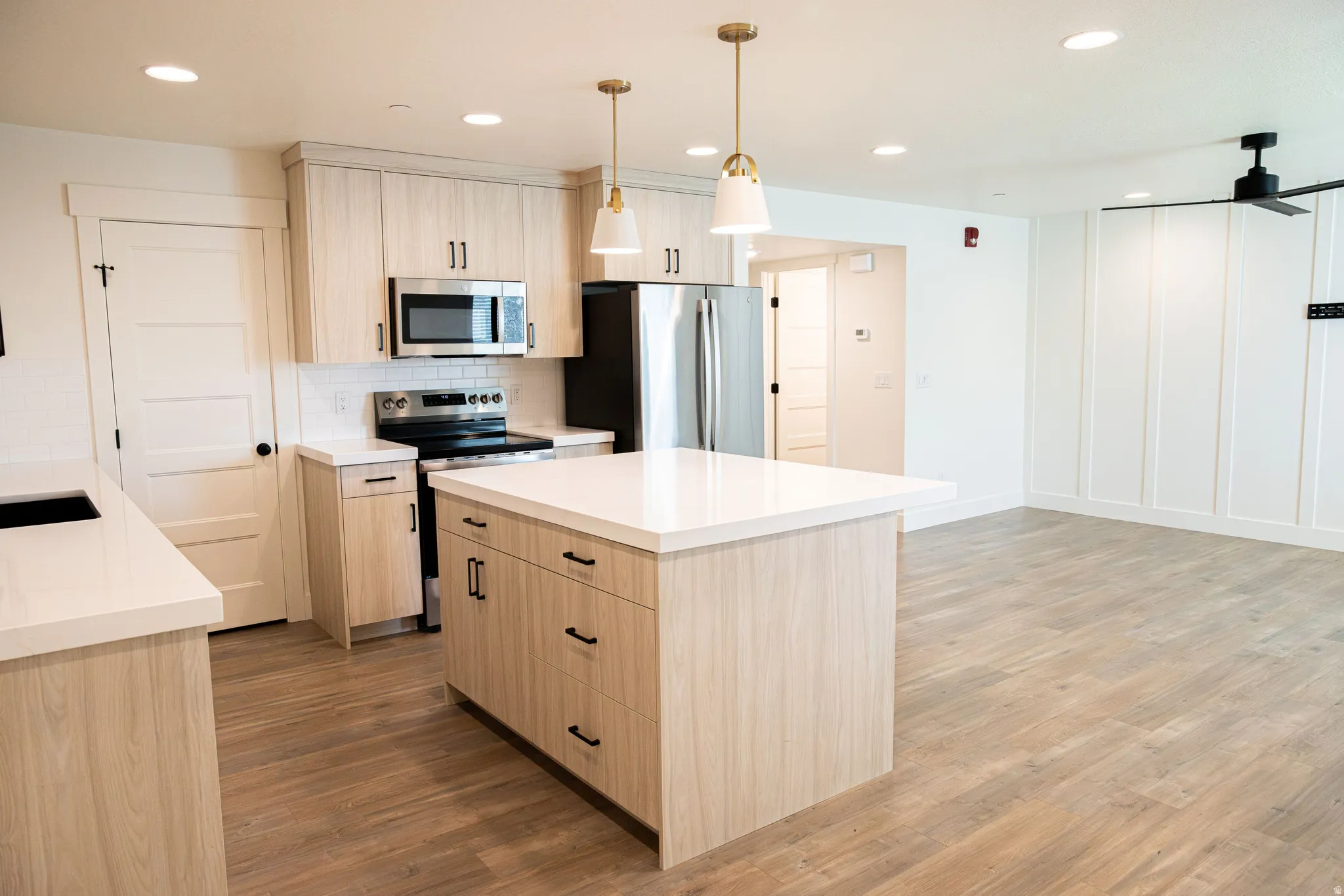 Kitchen featuring an island, full suite of stainless steel appliances, neutral wood-finish cabinetry, white countertops, and recessed lighting
