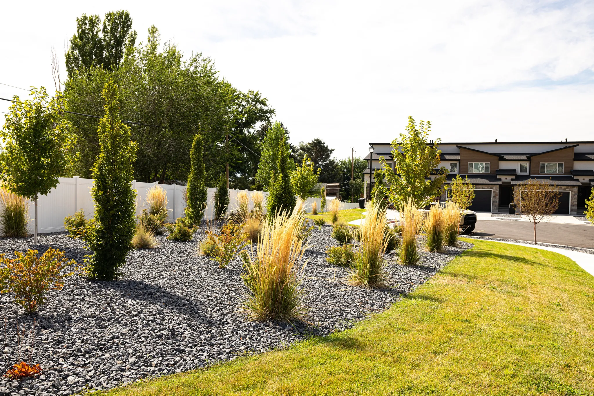Landscaped front yard featuring gravel beds, ornamental grasses, and mature trees