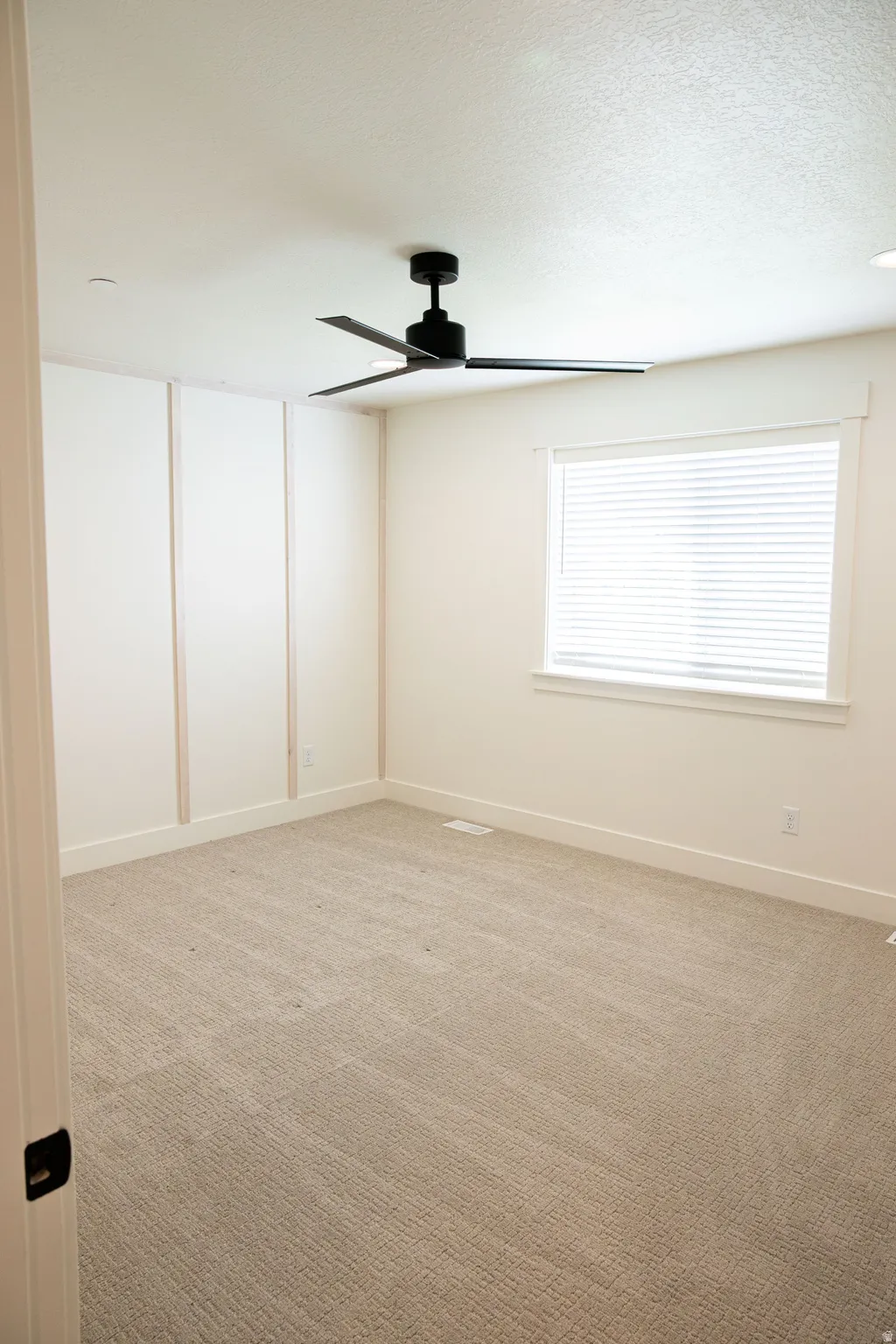 Plush carpeting, paneling accents, modern ceiling fan, and window with blinds