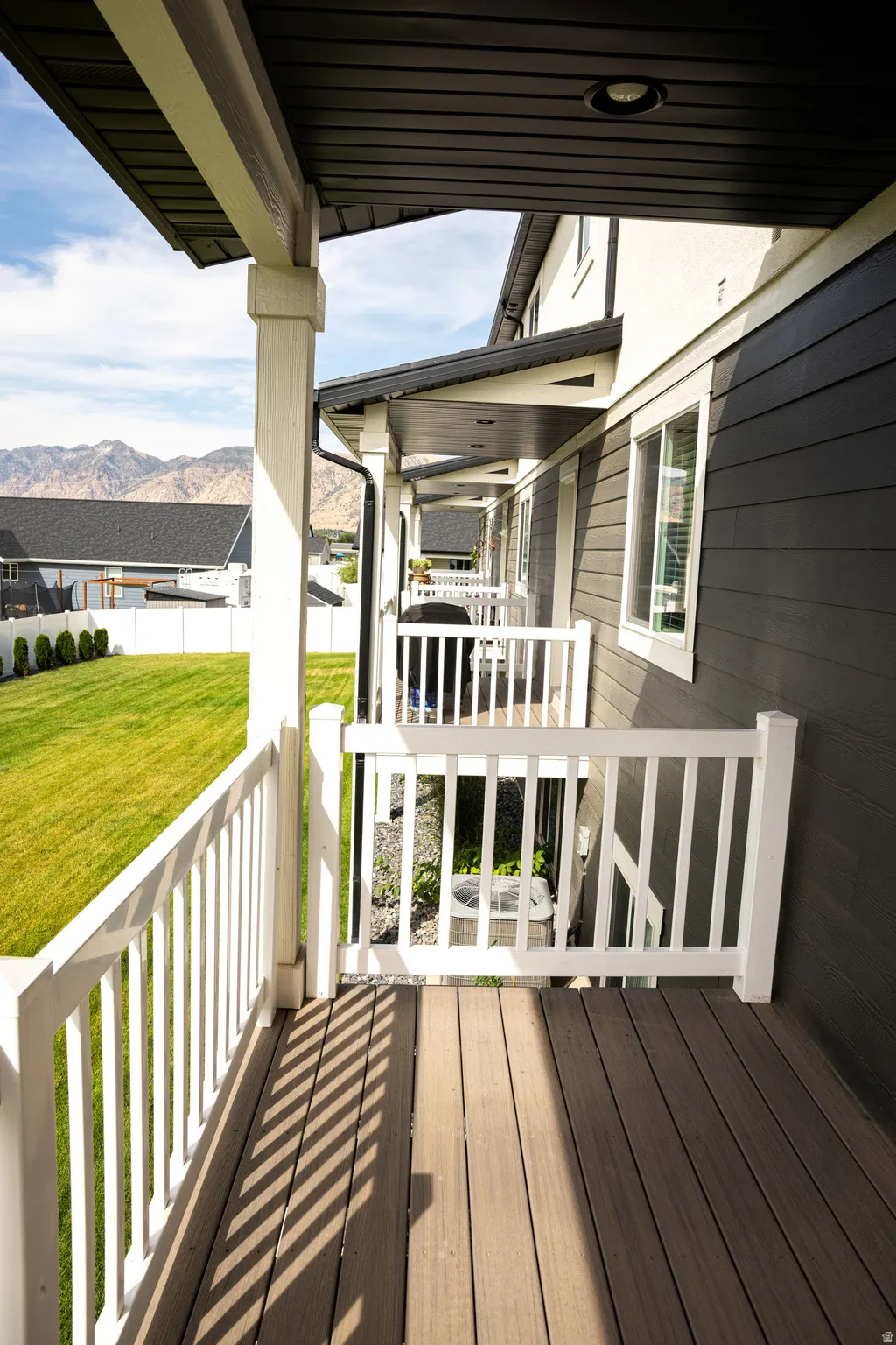 Covered porch with wood-finish decking, white railings, and recessed lighting