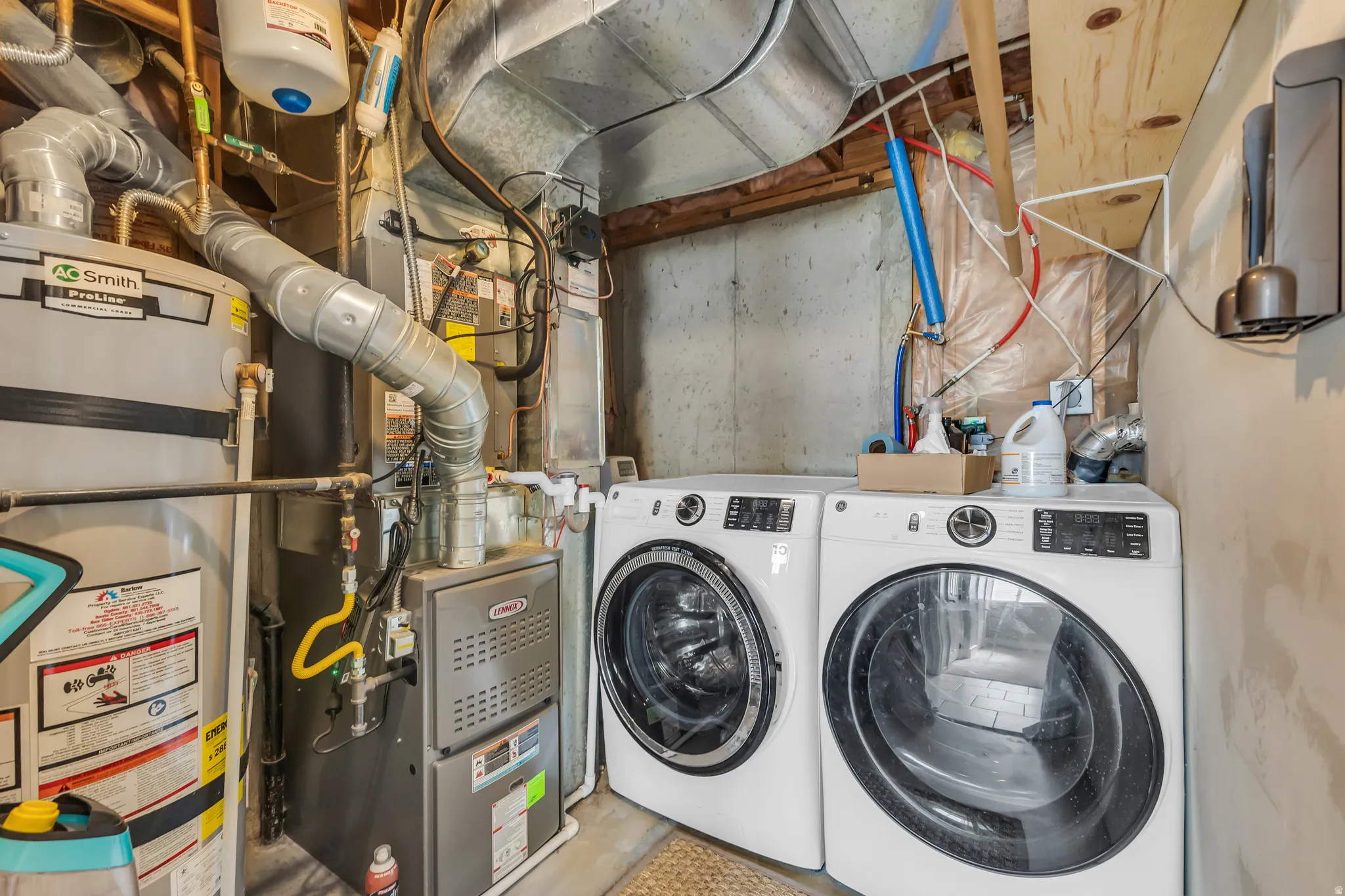 Utility area featuring a water heater, furnace, and side-by-side washer and dryer