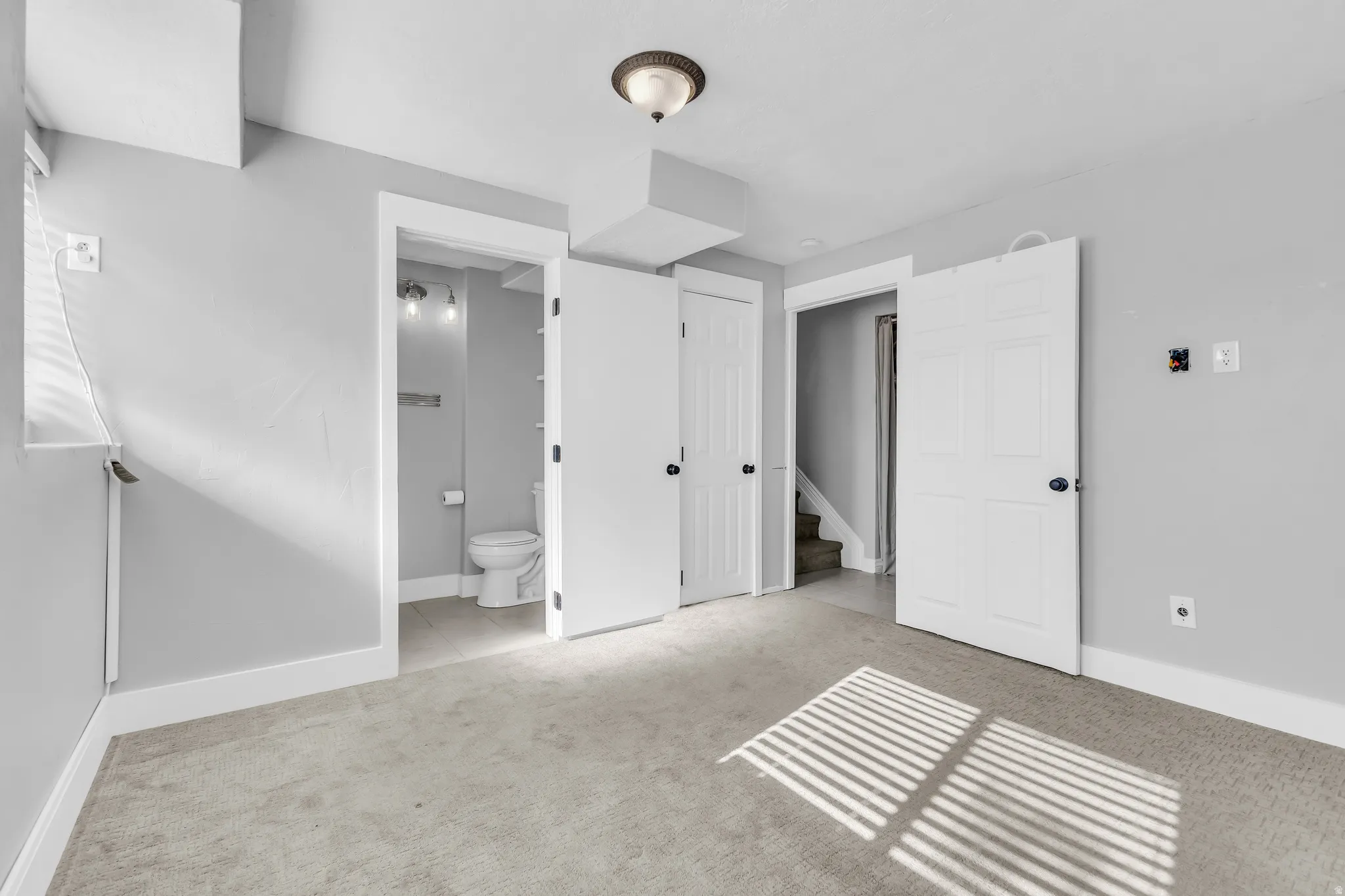 Neutral wall color, wall-to-wall carpeting, overhead light fixture, white trim, and doors with black hardware