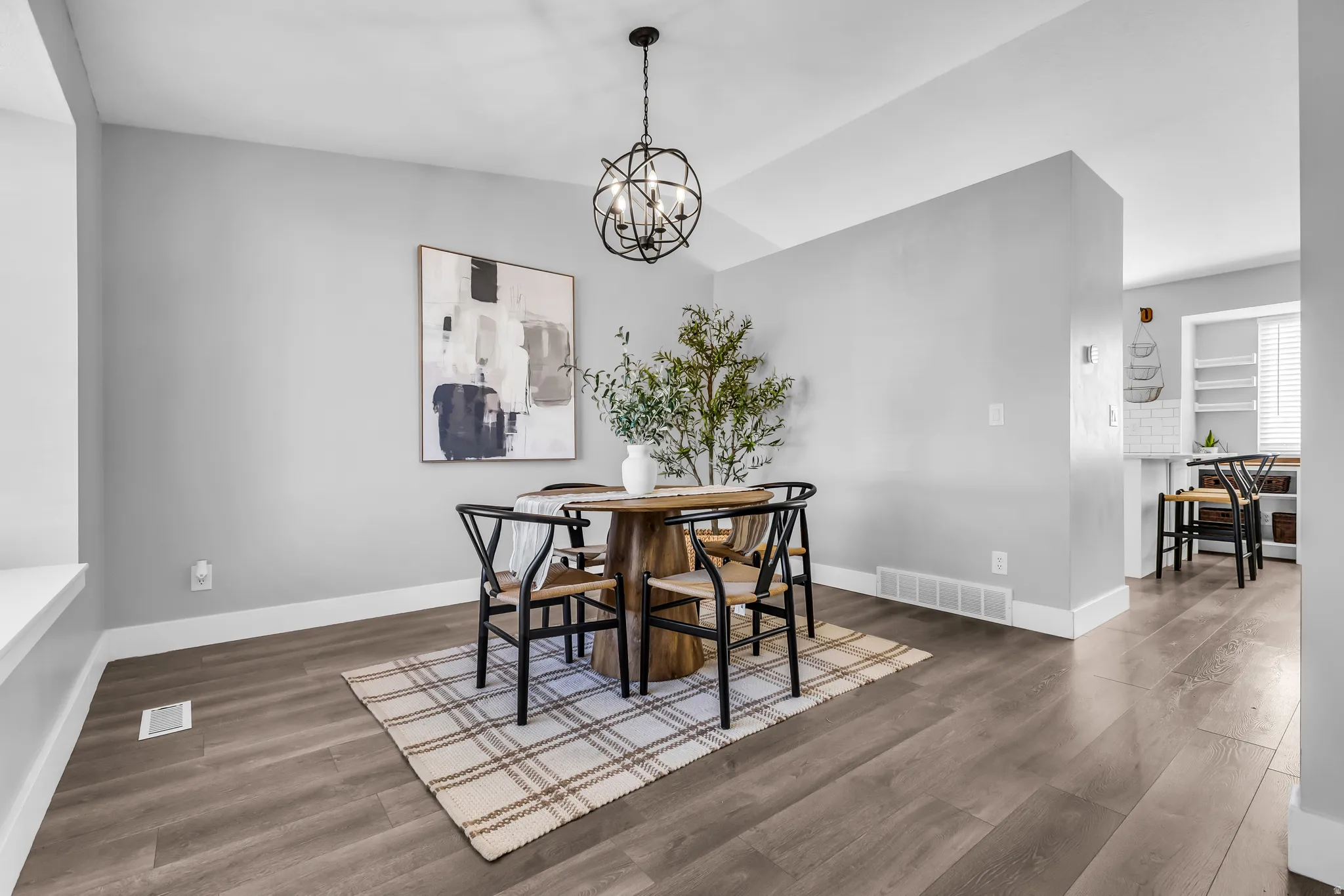 Wood-finish flooring throughout, a modern spherical chandelier, a built-in window bench, and a partial wall defining the space