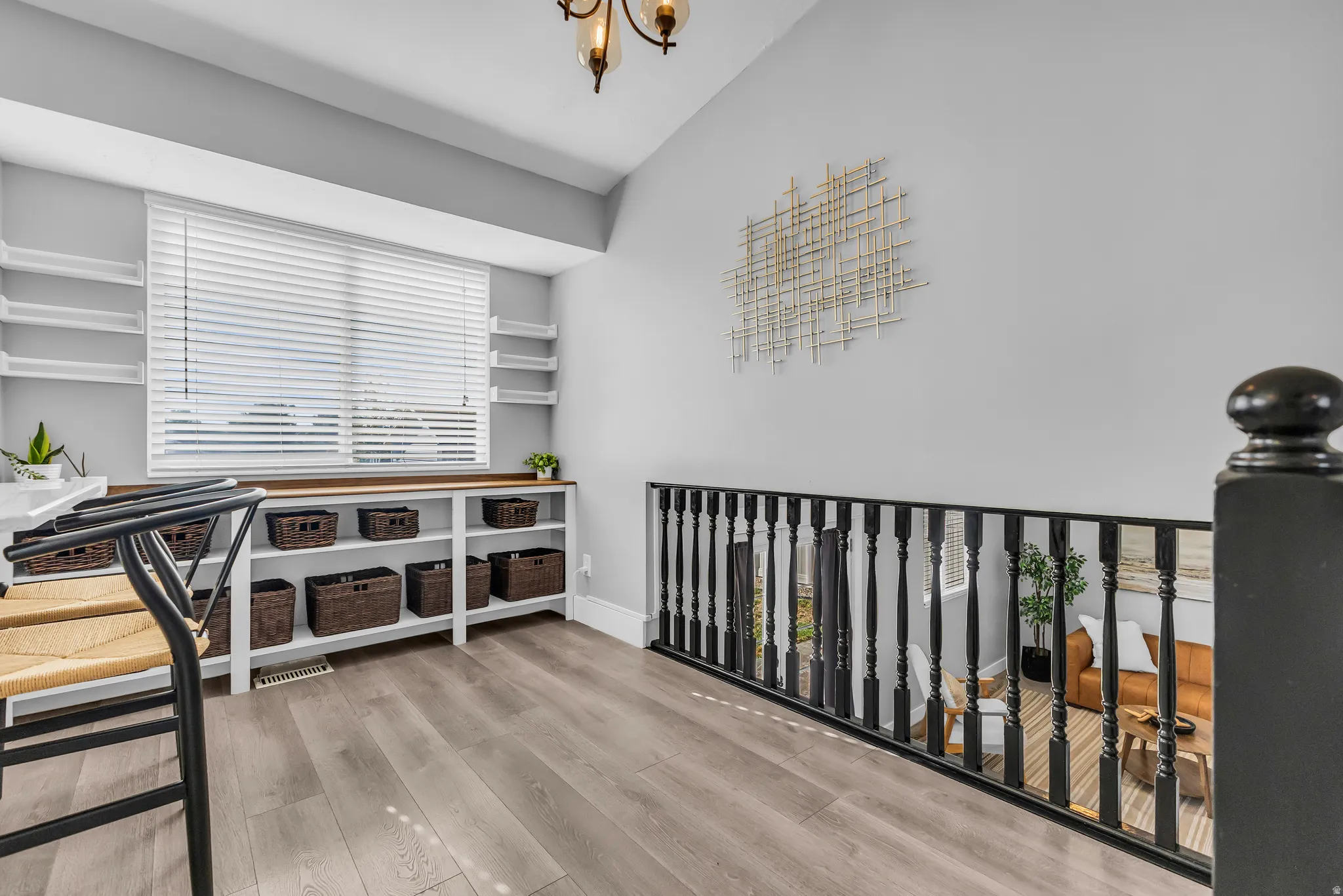 Wood-finish flooring, built-in shelving, white window blinds, and a black baluster railing