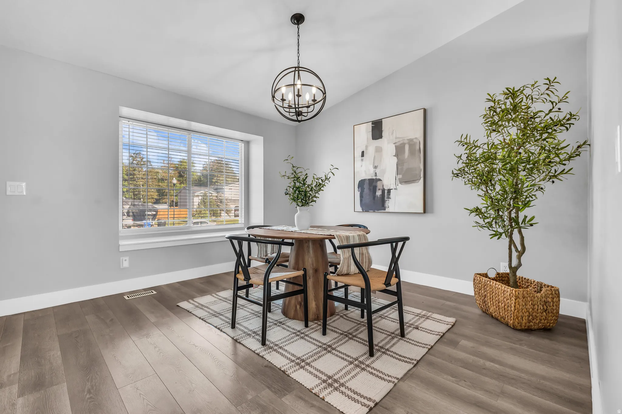 Expansive window with blinds, wood-finish flooring, white baseboards, and a spherical black chandelier