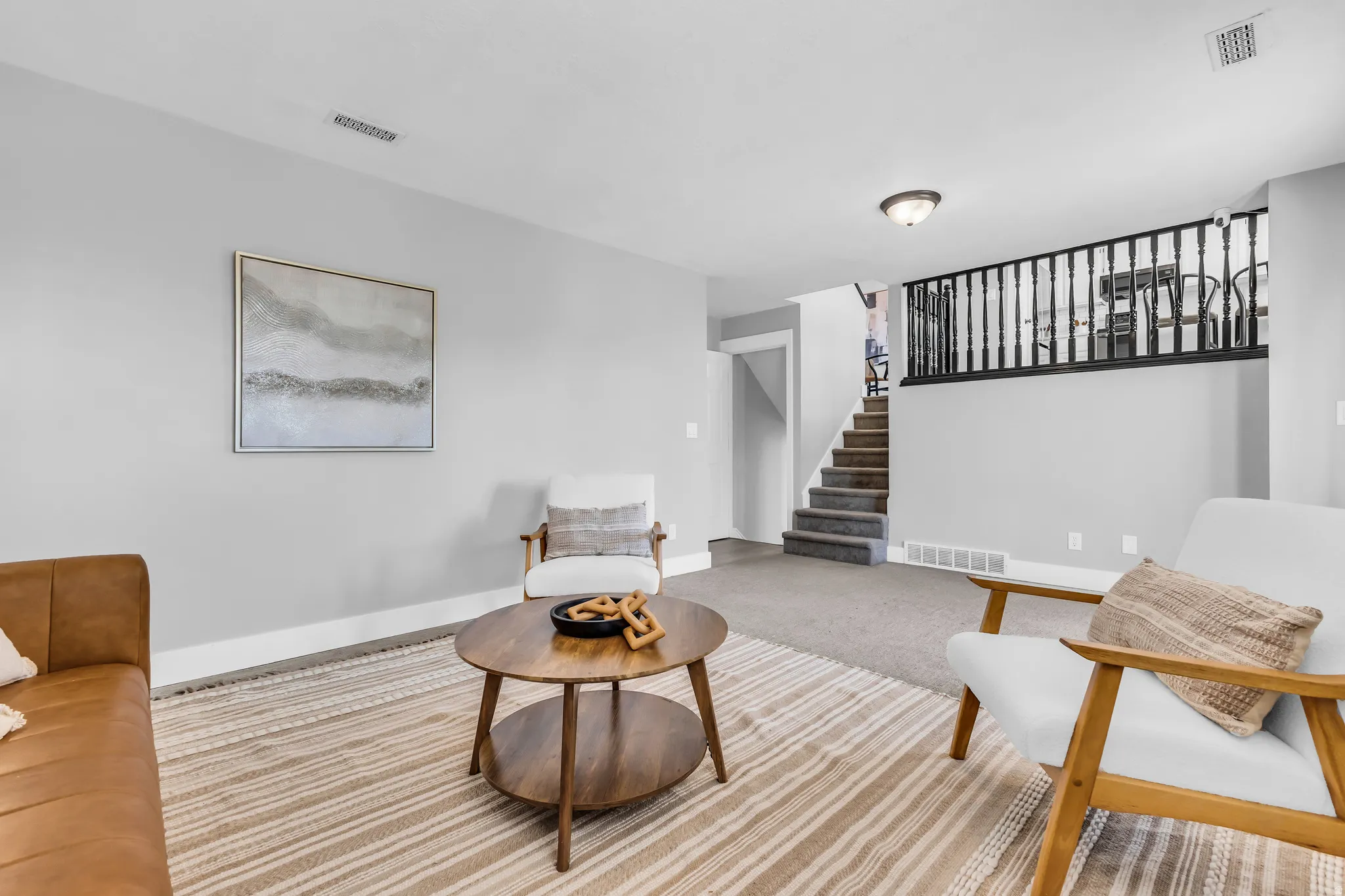Recessed overhead lighting, light gray wall paint, staircase with carpeted treads, dark wood banister, and a semi-flush mount ceiling light fixture