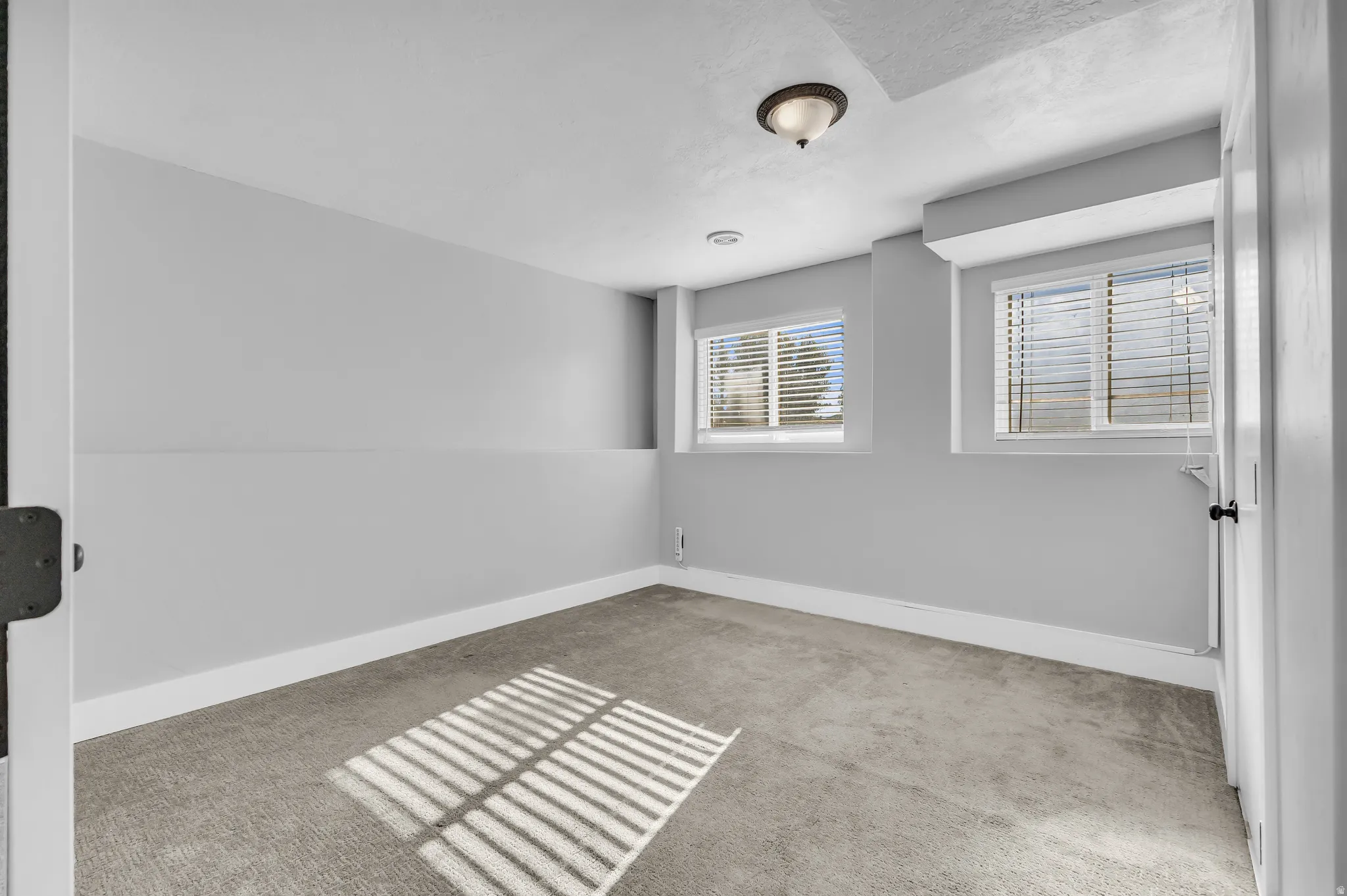 Recessed lighting, two windows, textured ceiling, wall-to-wall carpeting, and a flush mount light fixture