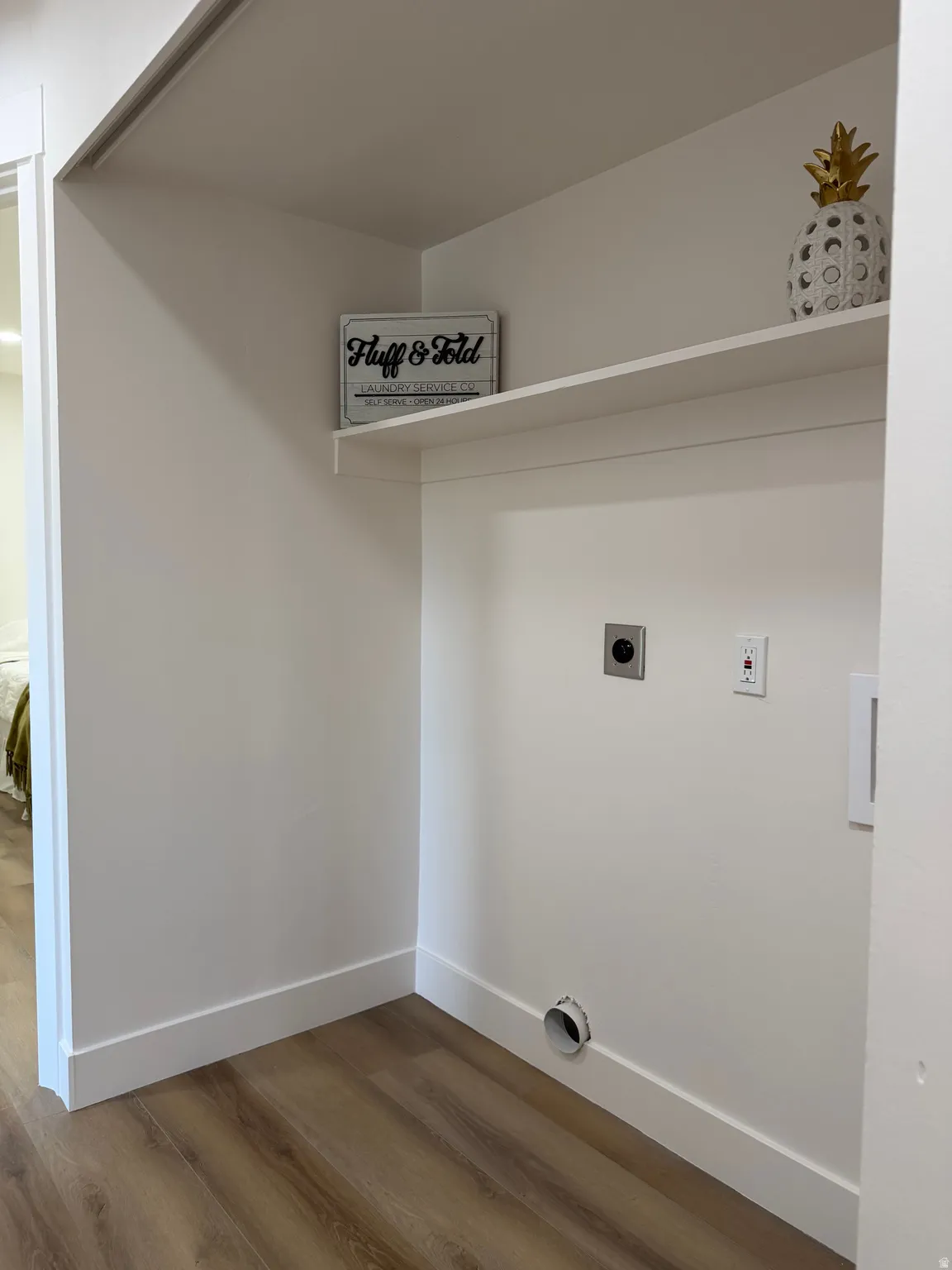 Laundry area featuring wood-finish flooring, white walls, and built-in shelving