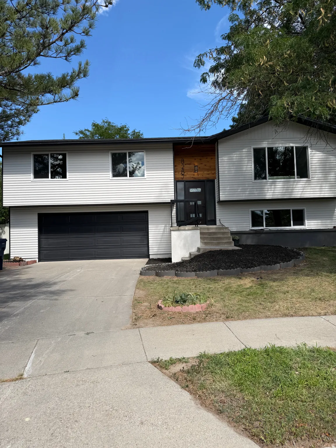 Split-level residence featuring white siding and black trim accents