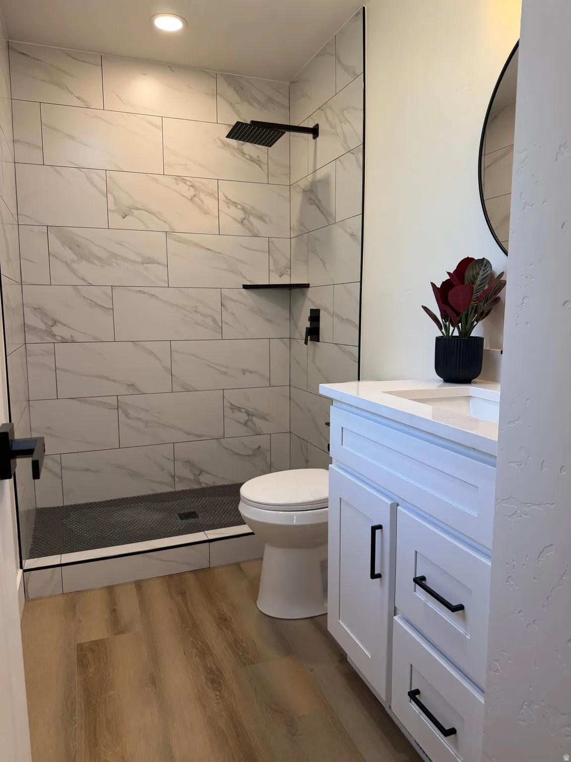 Walk-in shower with large format wall tiles and a black rain showerhead