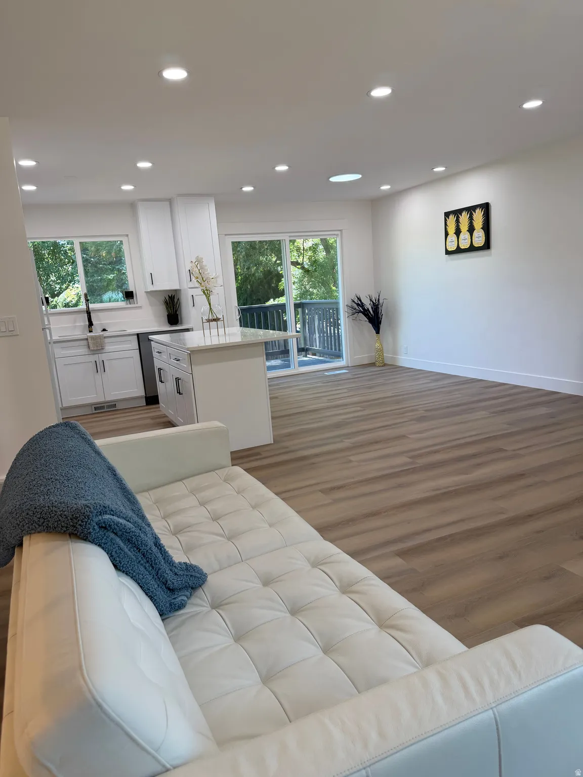 Open-concept living space featuring wood-finish flooring, recessed lighting, and a kitchen island with stone countertop