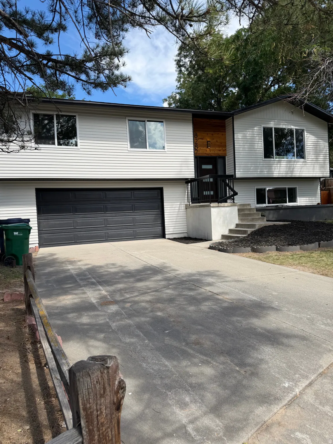 Split-level residence featuring white siding, a two-car garage, and a concrete driveway