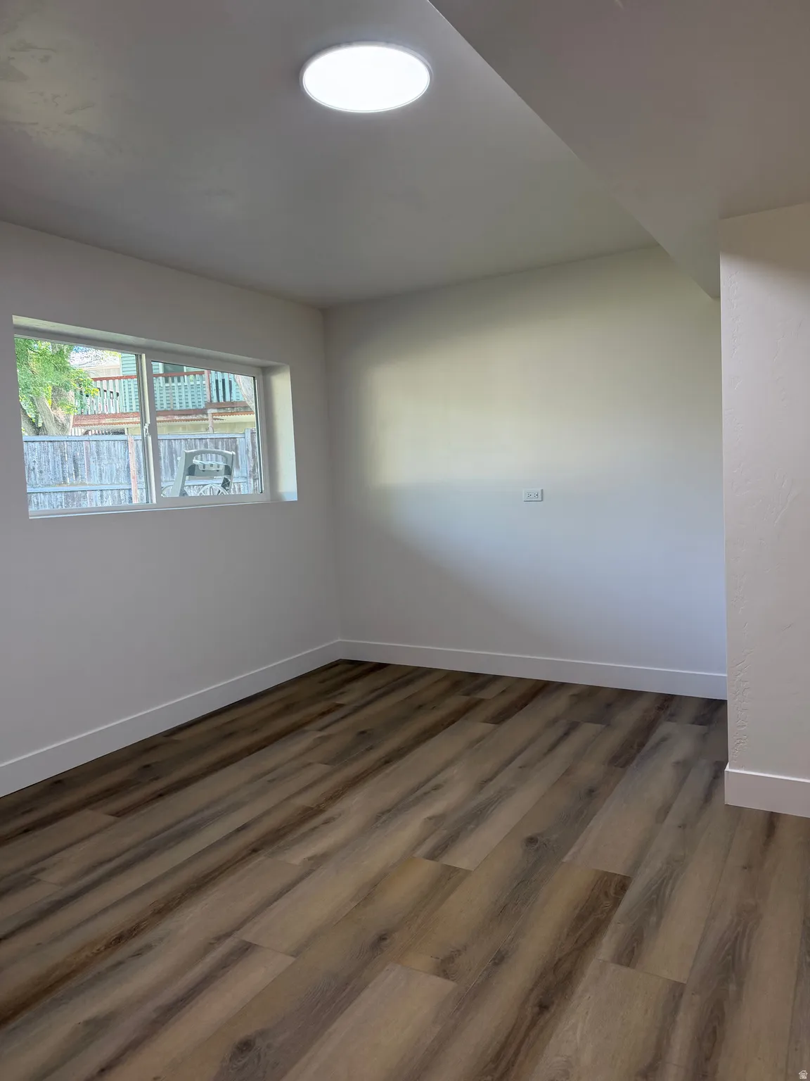 Recessed ceiling light, white walls, wood-finish flooring, and a horizontal window
