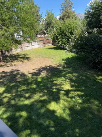 Enclosed backyard featuring a wood fence perimeter and mature trees