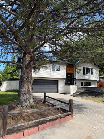 White siding exterior with a dark garage door, concrete driveway, and split-level entry