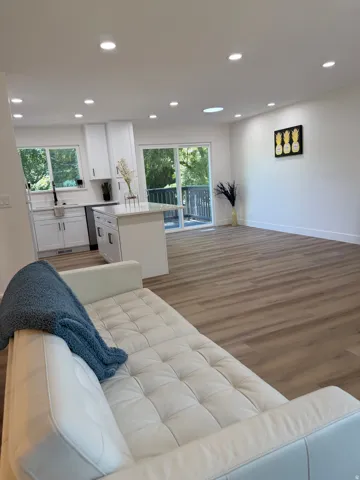 Open-concept living space featuring wood-finish flooring, recessed lighting, and a kitchen island with stone countertop