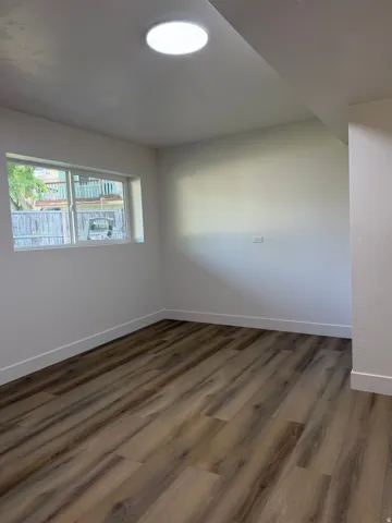 Recessed ceiling light, white walls, wood-finish flooring, and a horizontal window