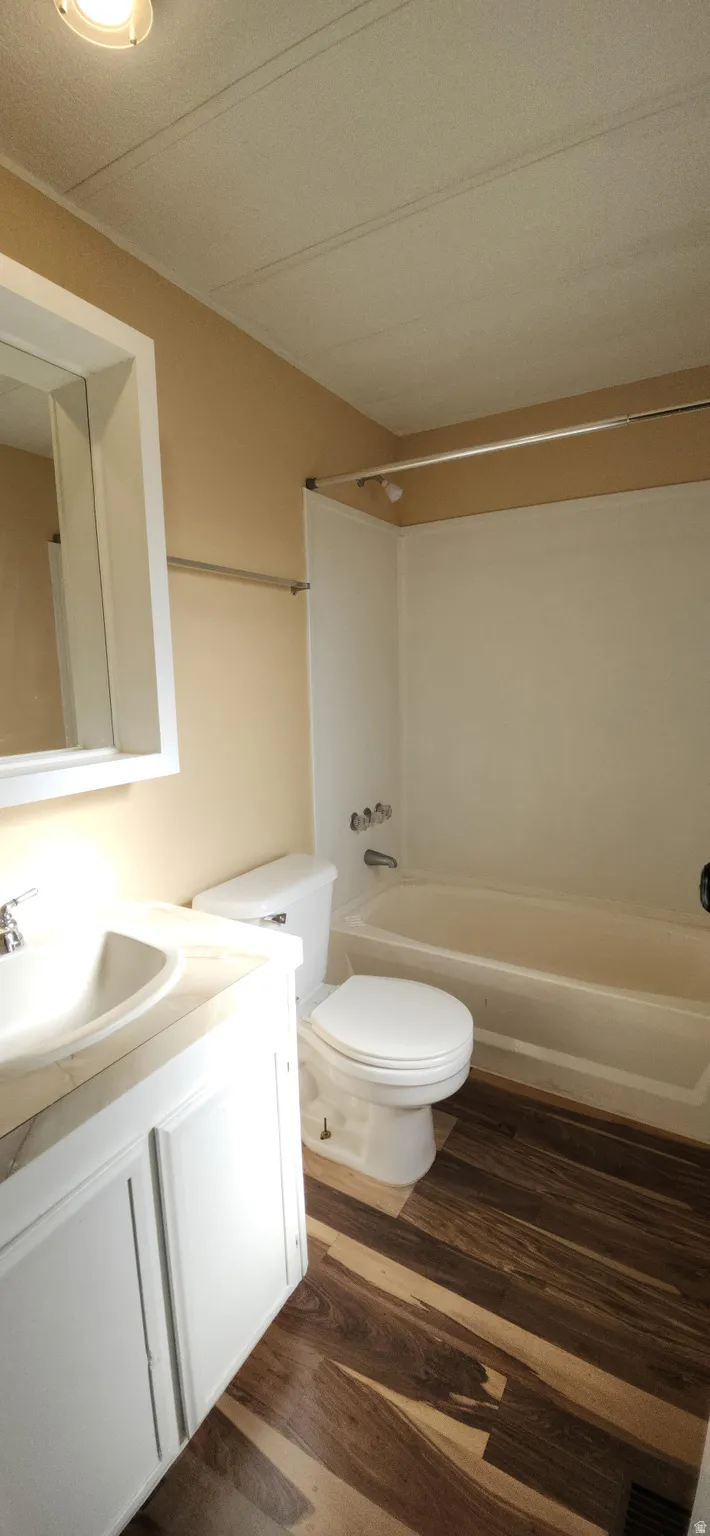 Bathroom featuring a white vanity with integrated sink, a white toilet, and a bathtub with shower surround