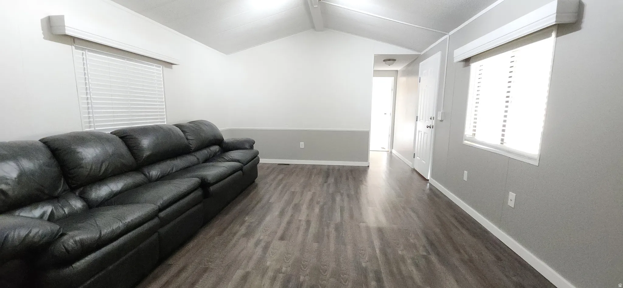 Wood-finish flooring, vaulted ceiling, white trim, and window blinds