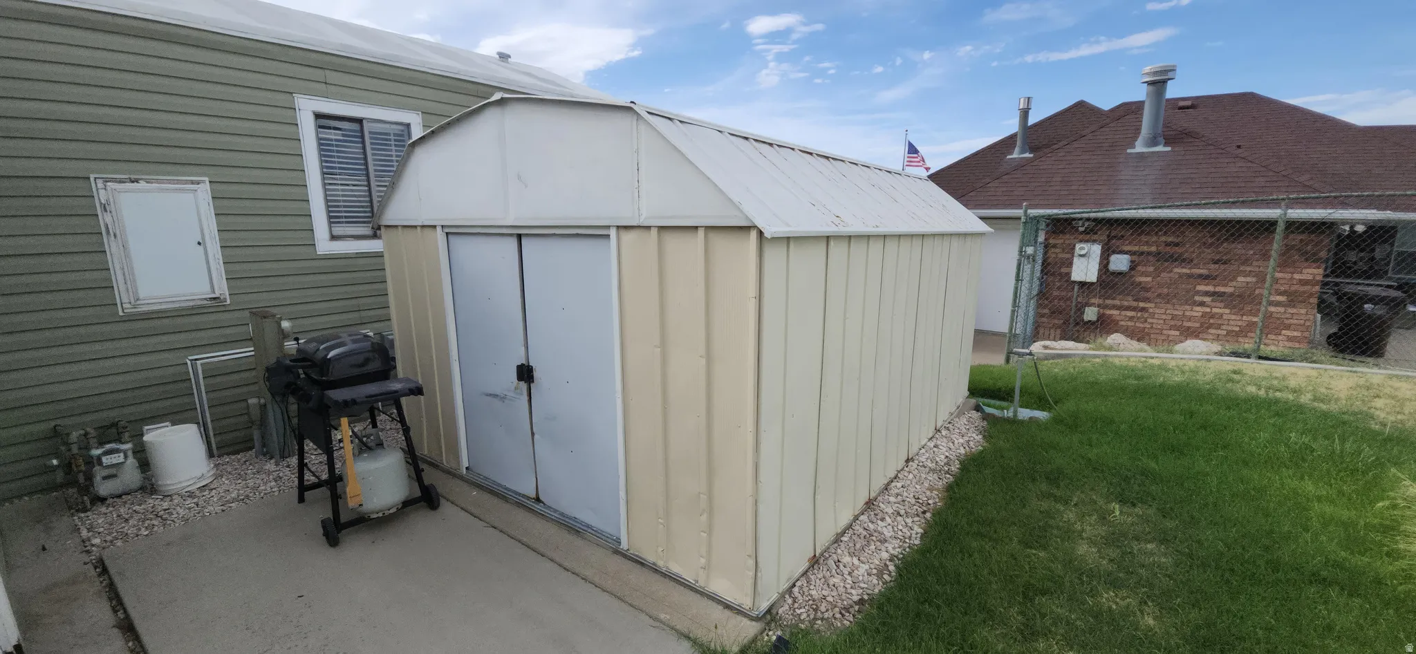 Metal storage shed with double doors, concrete slab foundation, and gravel perimeter