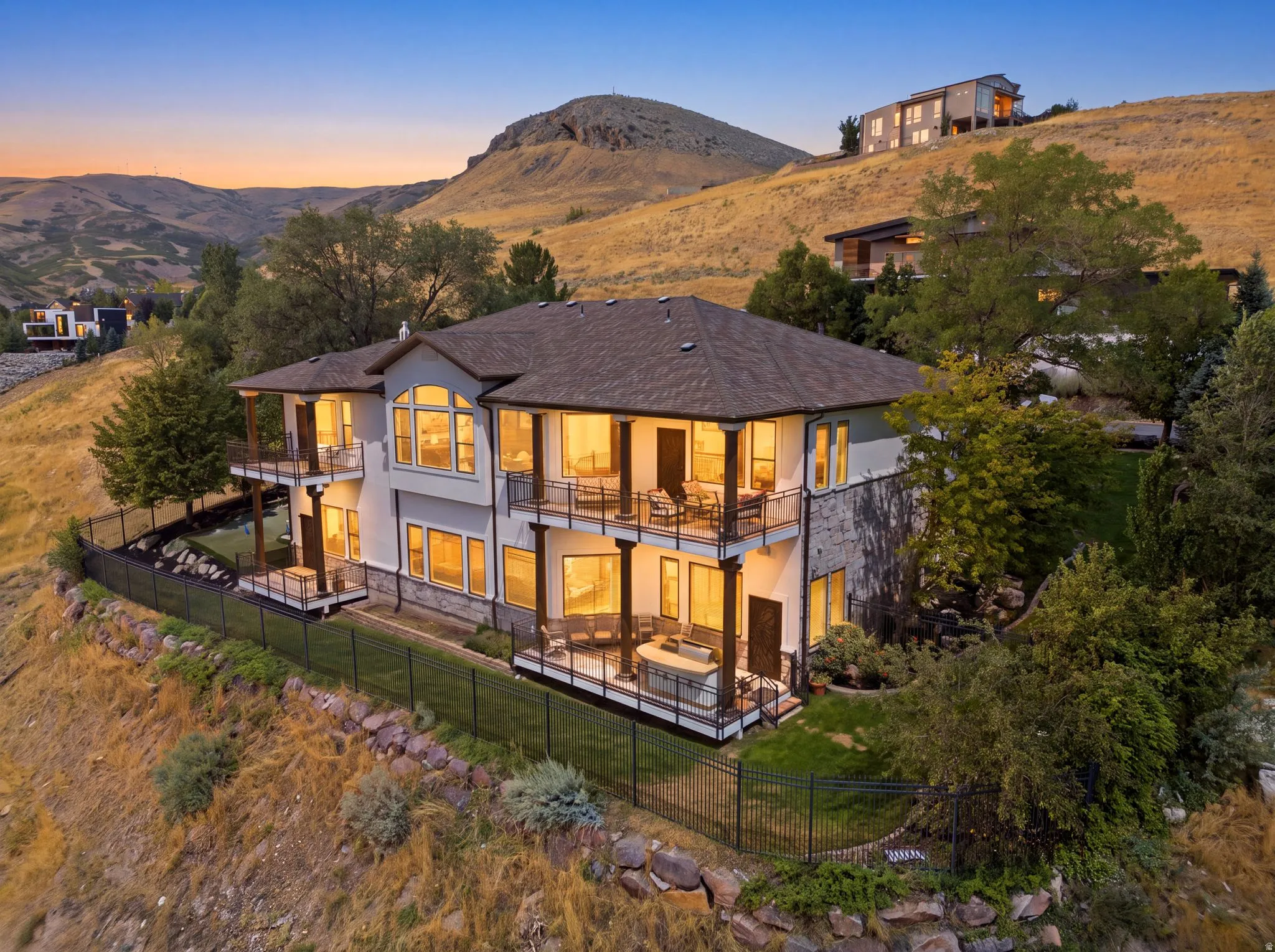 Multi-level residence featuring extensive outdoor balconies, a stucco and stone exterior, large windows, and a dark shingle roof