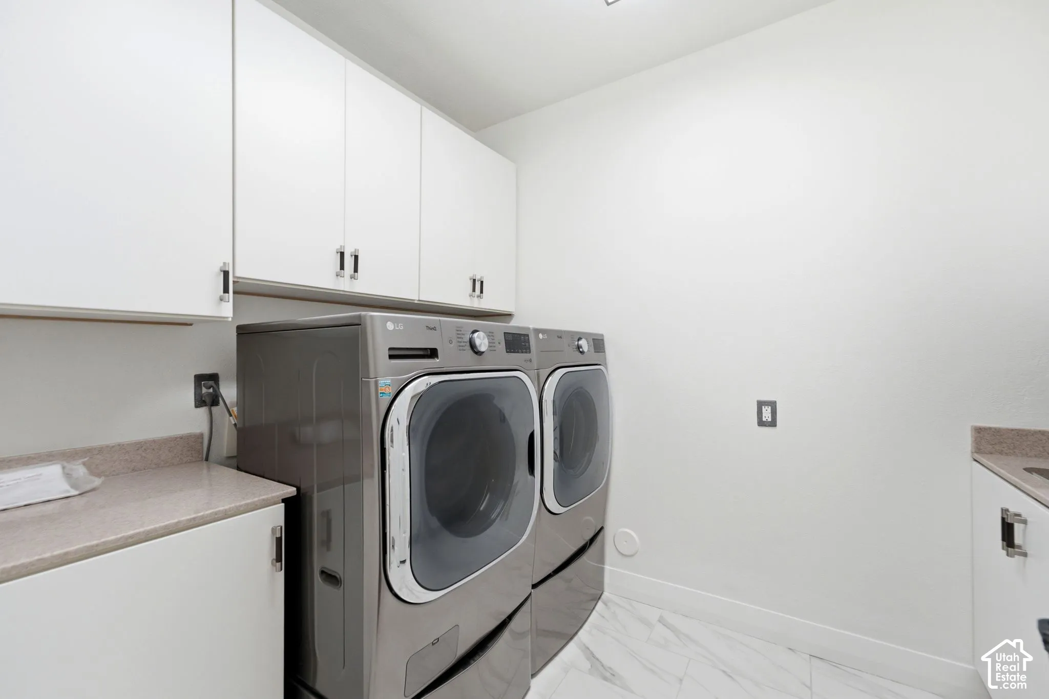 White cabinetry with brushed nickel hardware, light-toned countertop, and integrated sink