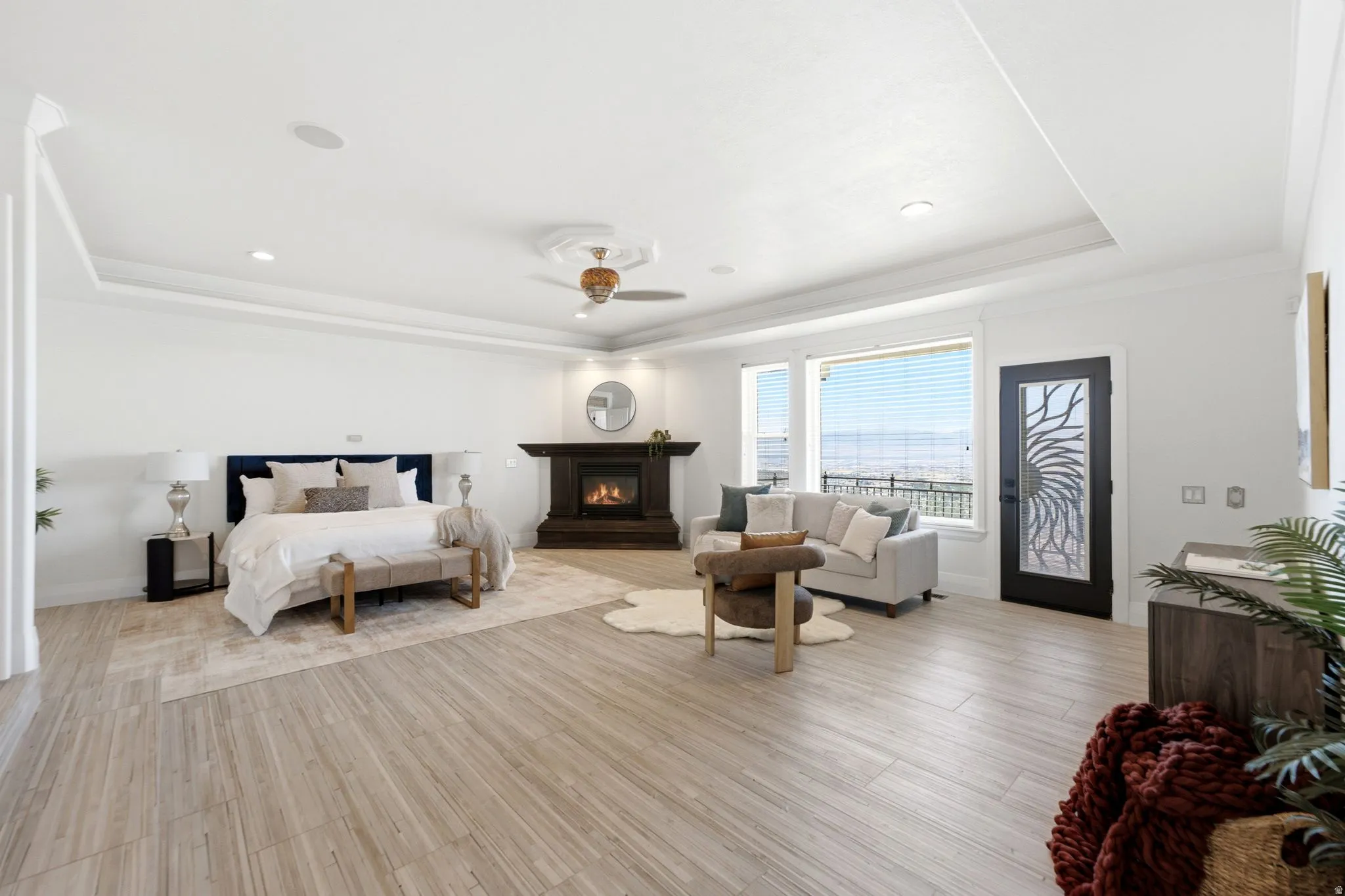 Spacious room featuring wood-finish flooring, a tray ceiling, and a built-in fireplace with a dark wood mantel