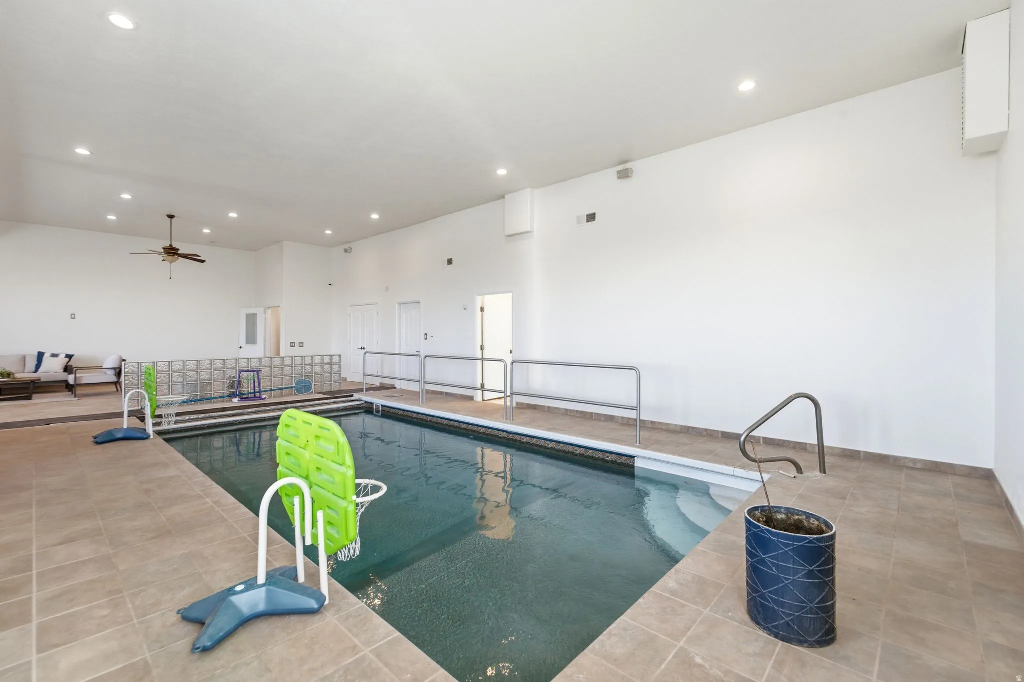 Indoor swimming pool featuring a tiled surround, integrated steps, and handrails