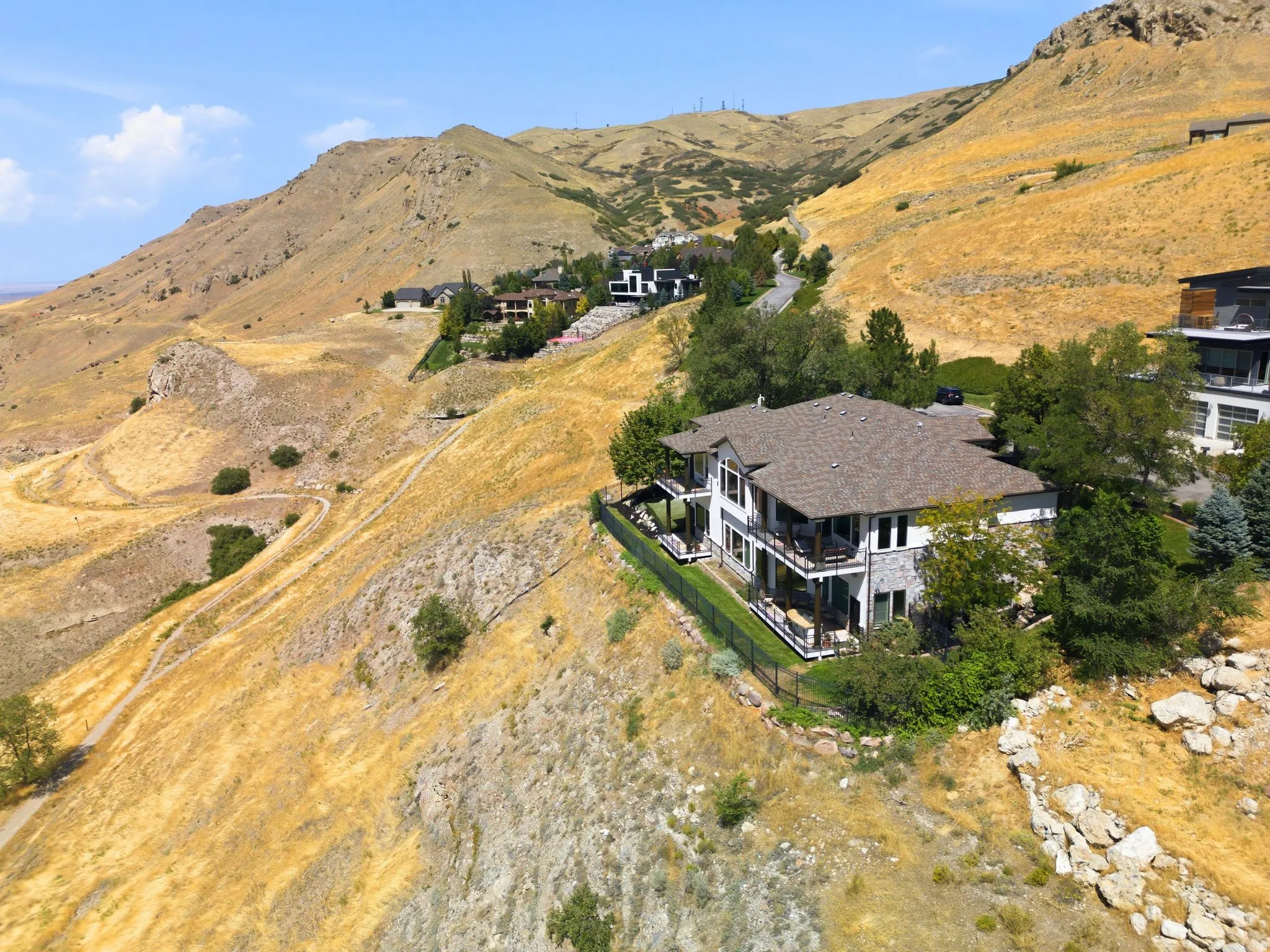 Hillside residence featuring multiple balconies, a stone and stucco exterior, and a fenced perimeter