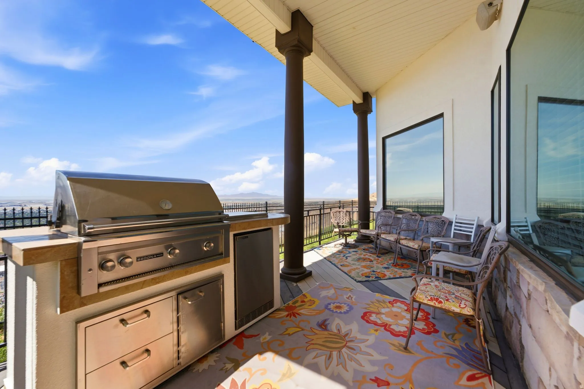 Covered outdoor patio featuring a built-in grill station, integrated stainless steel appliances, and large windows