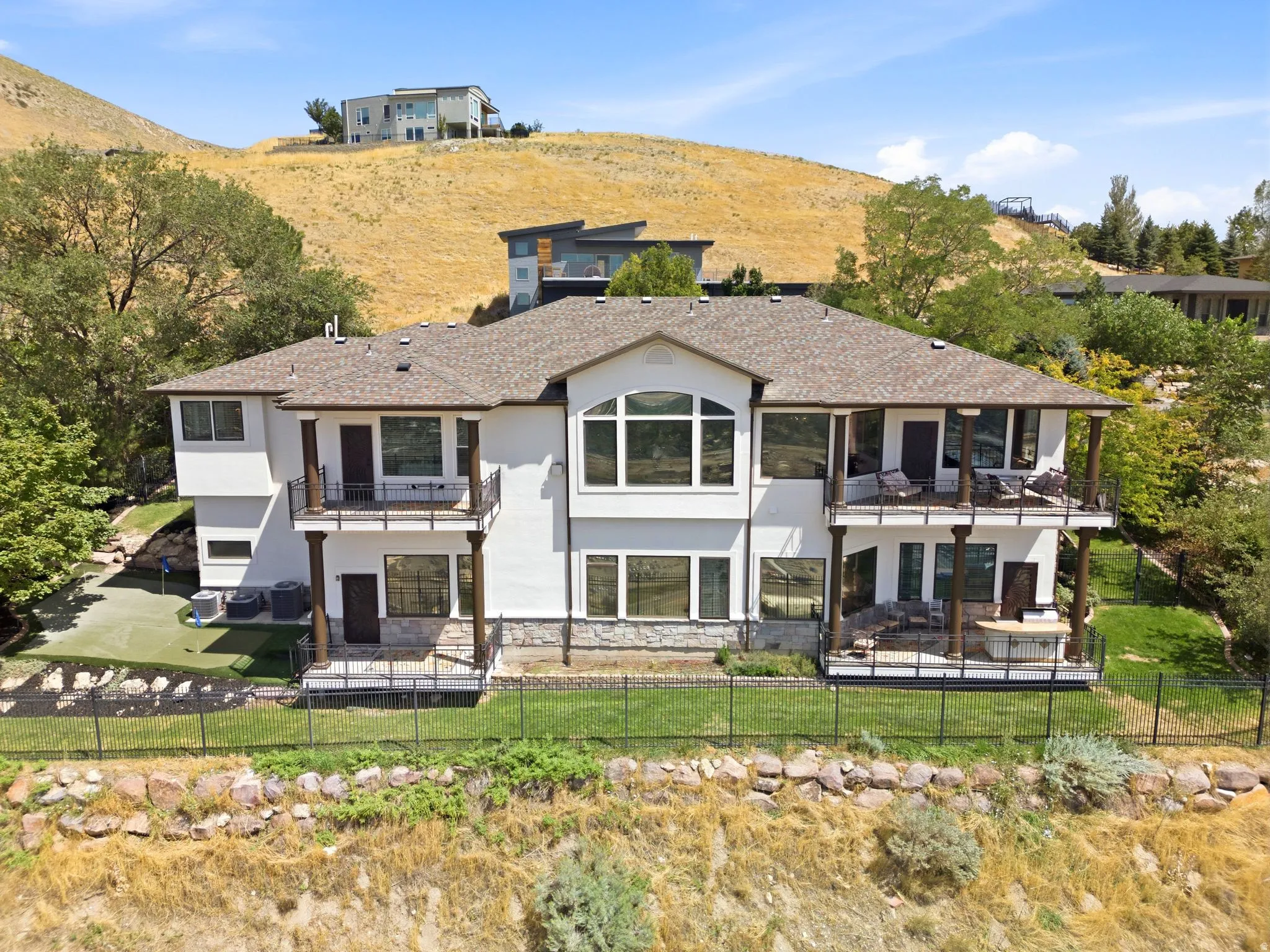 Multi-level exterior with multiple balconies, a lower-level patio, and a putting green
