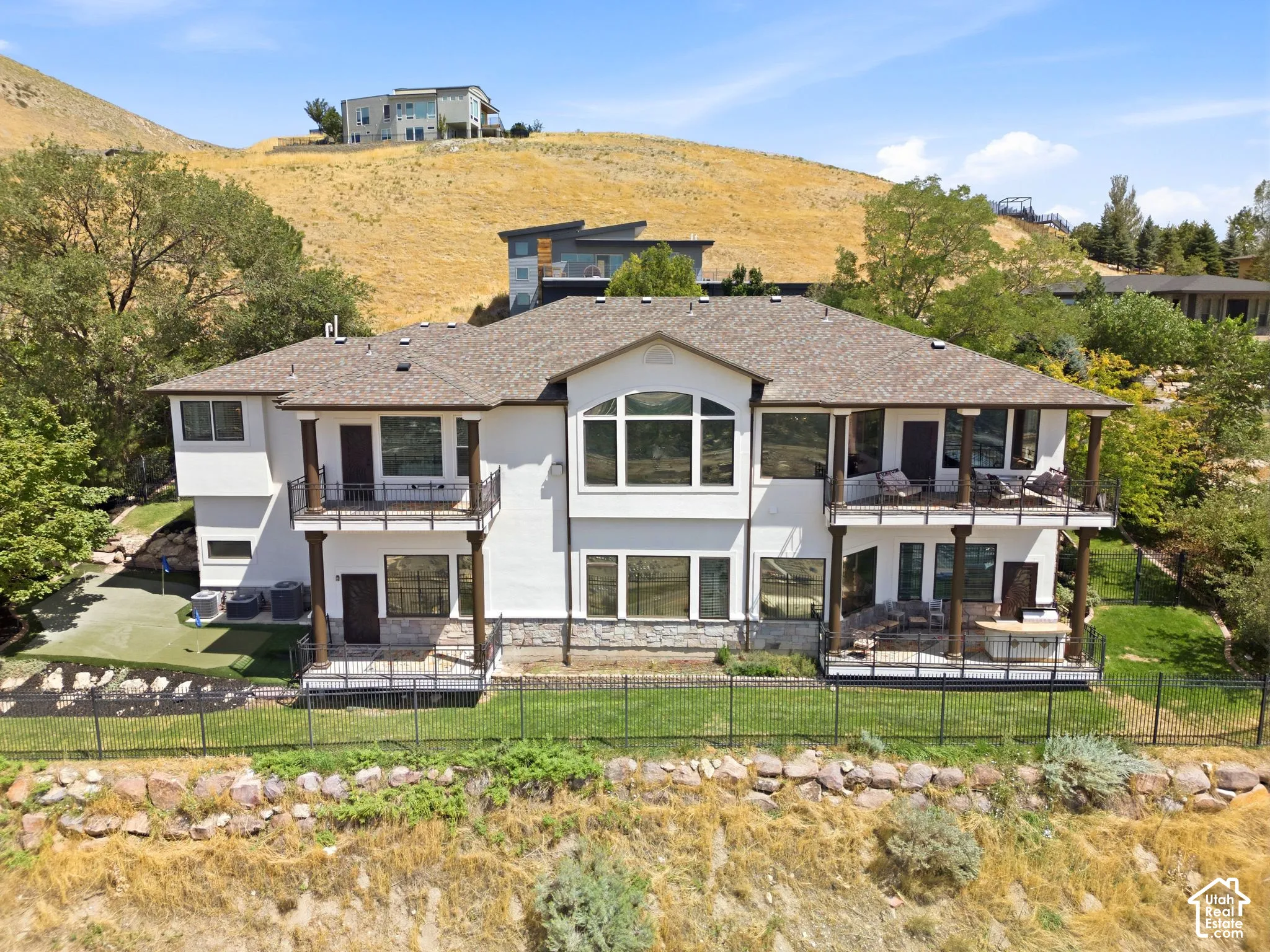 Multi-level exterior with multiple balconies, a lower-level patio, and a putting green