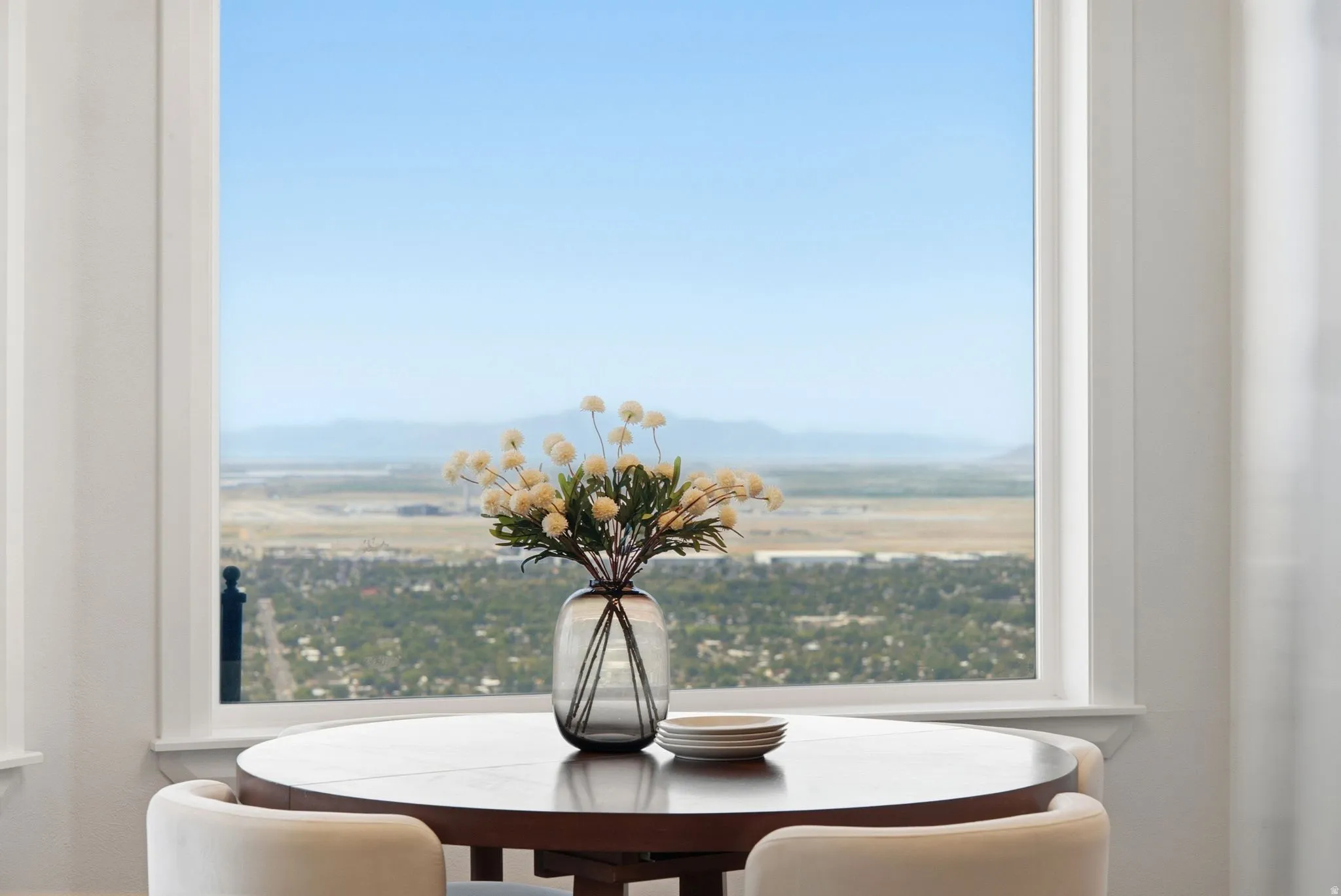 Expansive window with white trim framing a distant mountain and city backdrop