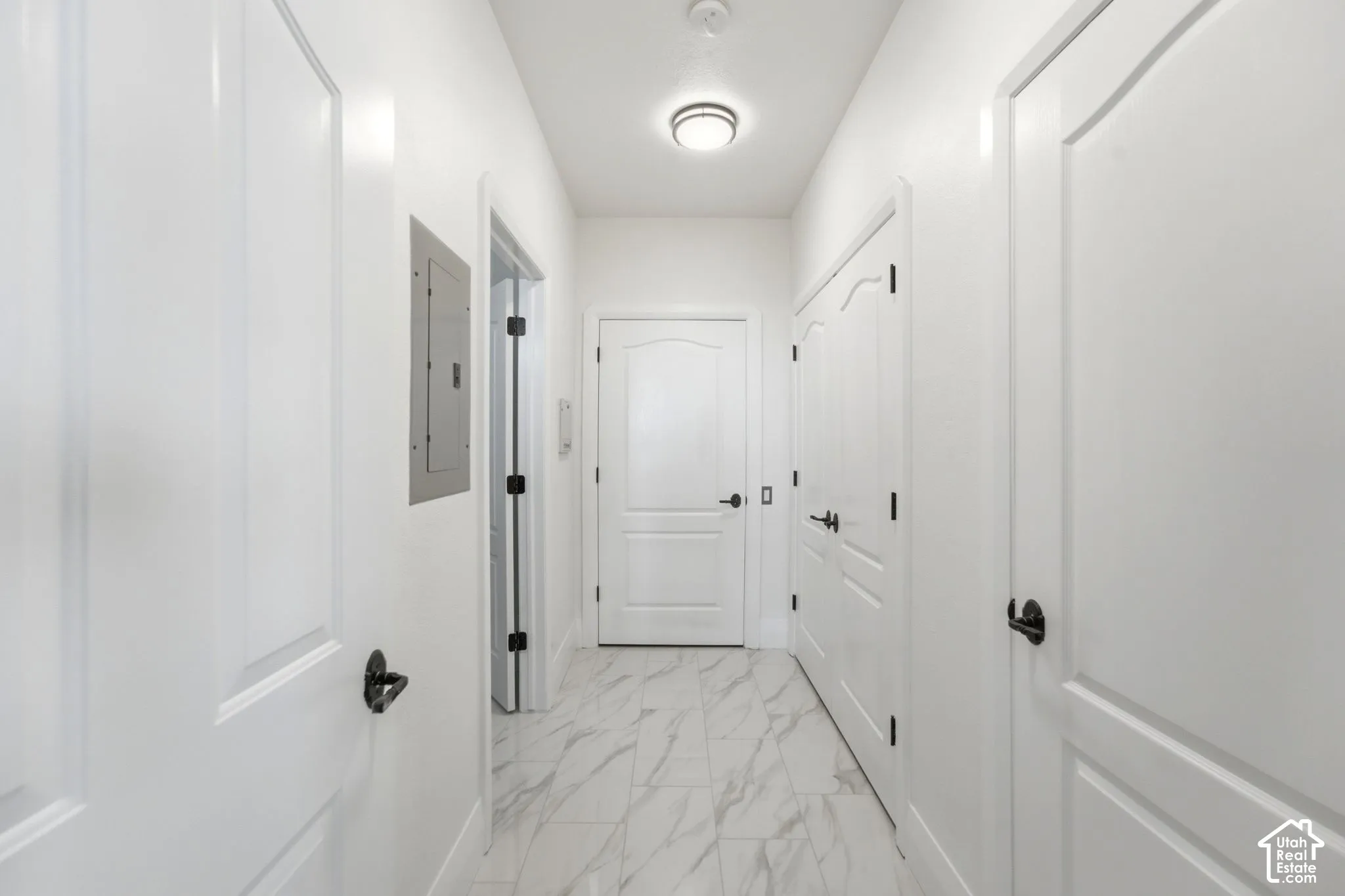 Hallway featuring white panel doors, matte black hardware, recessed lighting, and marble-look tile flooring