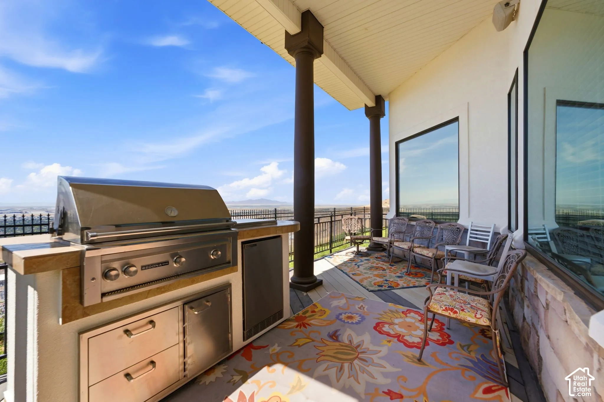Covered outdoor patio featuring a built-in grill station, integrated stainless steel appliances, and large windows
