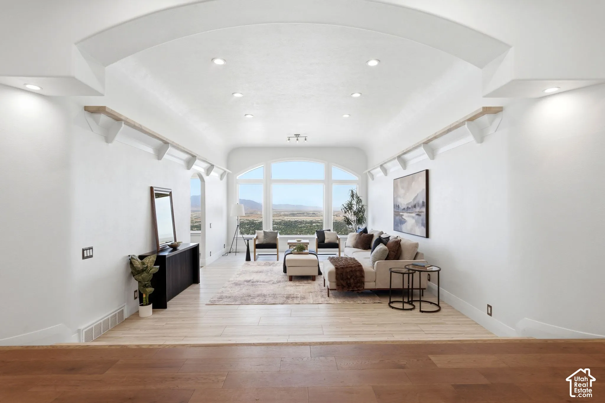 Archway entrance with recessed lighting and built-in shelving, wood-finish flooring, and expansive arched windows