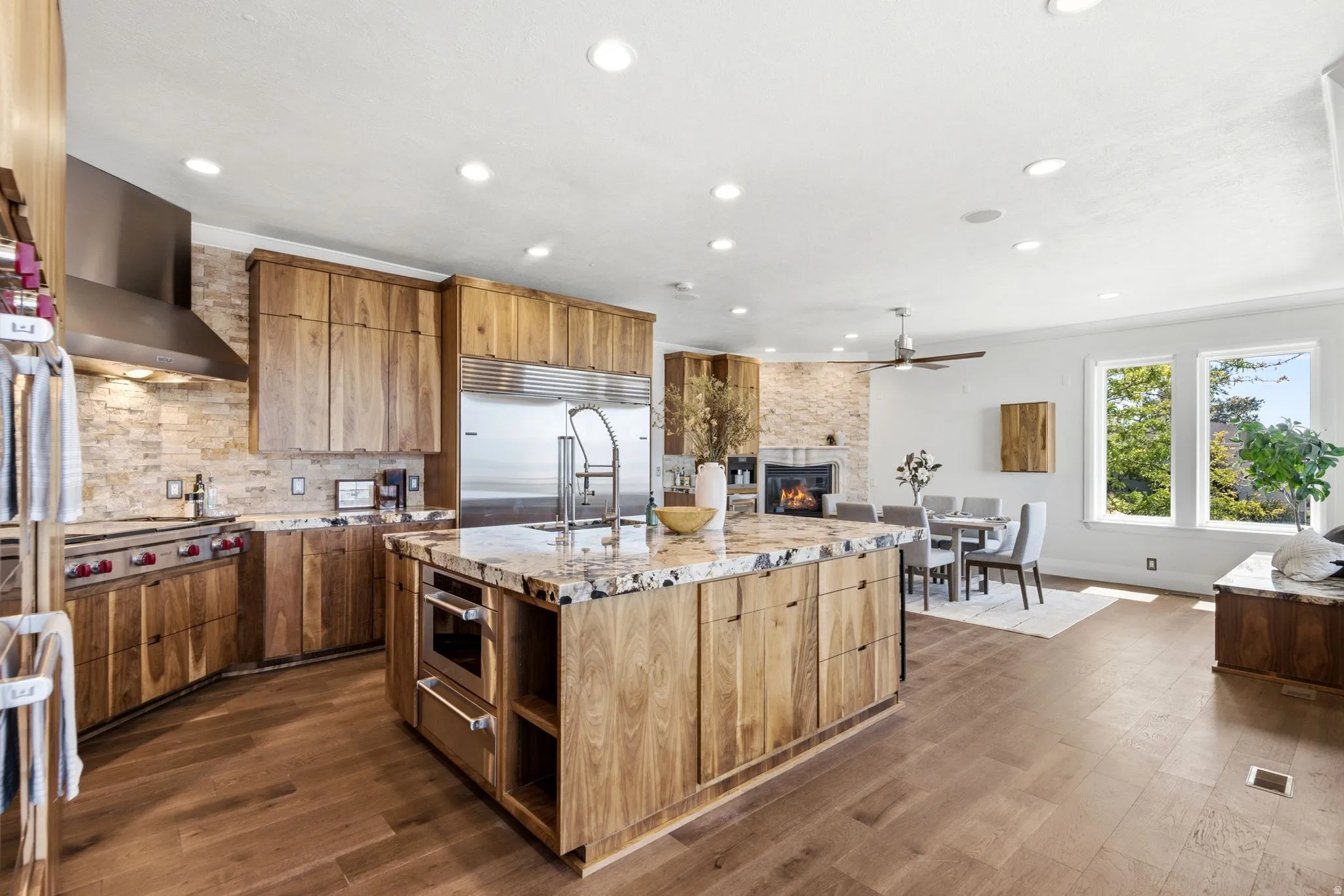 Open-concept kitchen featuring wood-finish cabinetry, a large kitchen island with integrated microwave, stainless steel appliances, and wood-finish flooring