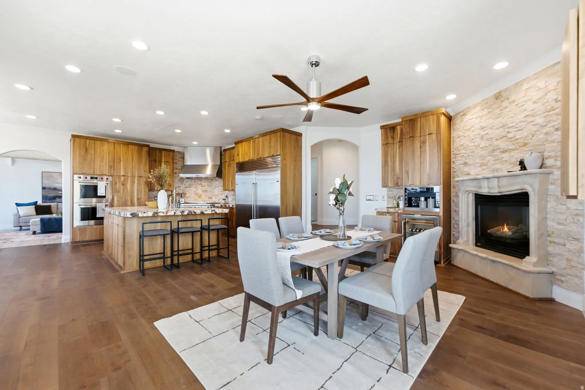 Hardwood flooring, stone accent wall, recessed lighting, built-in double oven, and a gas fireplace