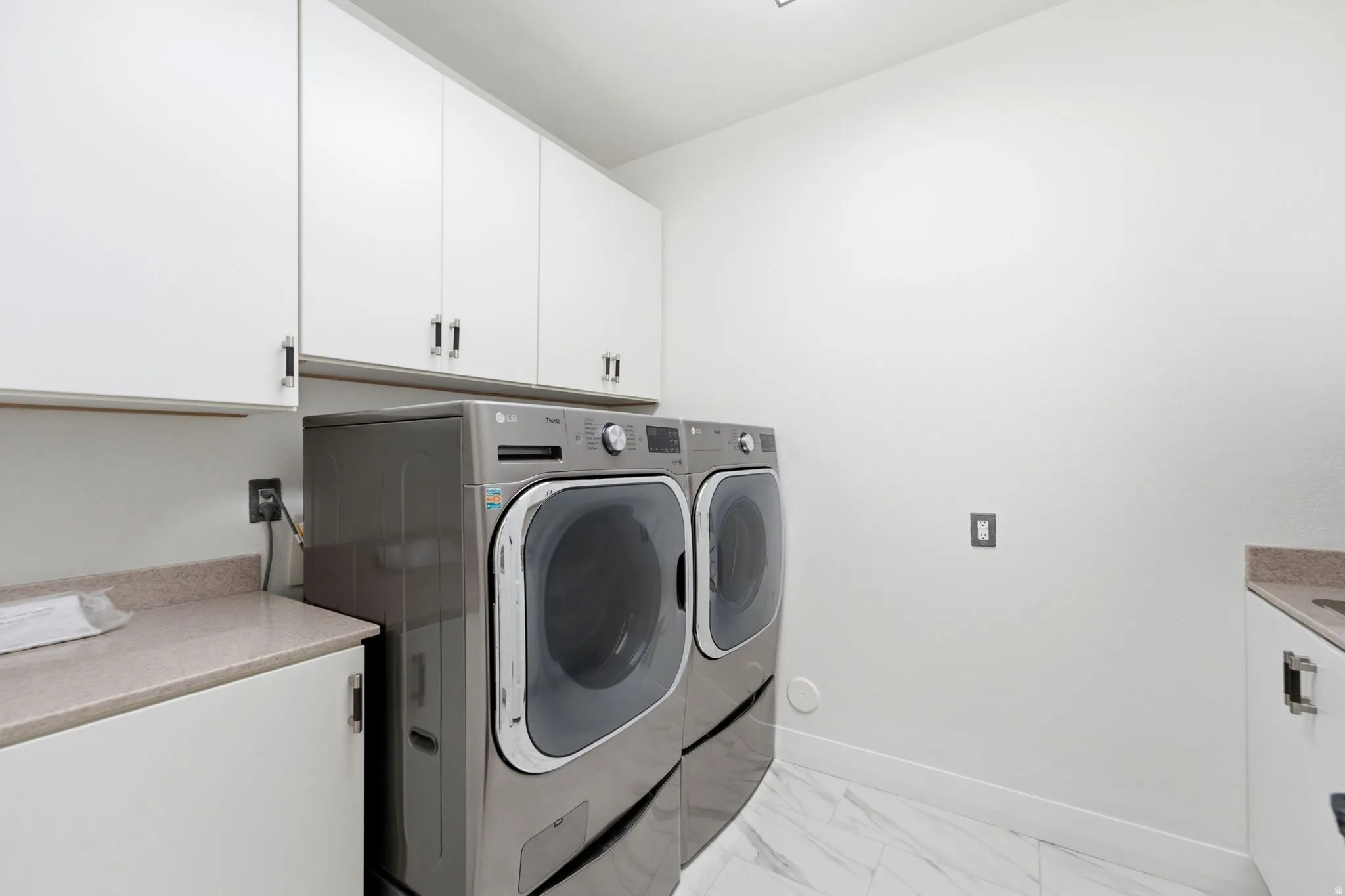 White cabinetry with brushed nickel hardware, light-toned countertop, and integrated sink