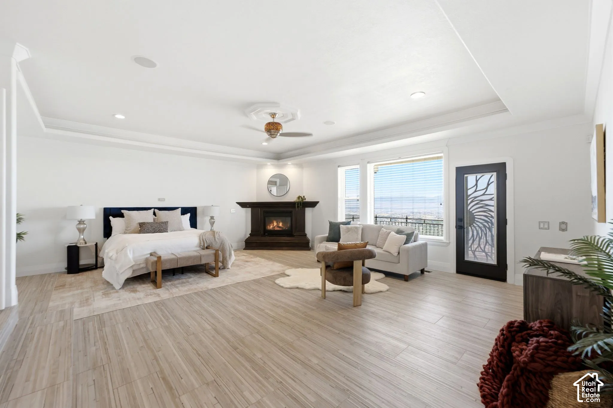 Spacious room featuring wood-finish flooring, a tray ceiling, and a built-in fireplace with a dark wood mantel