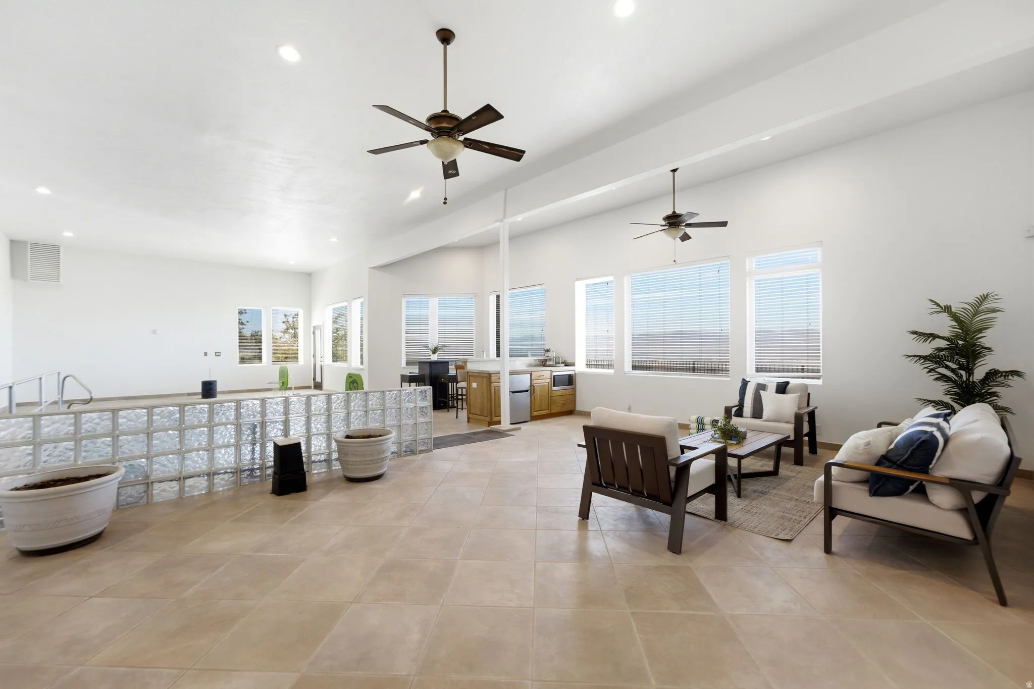Expansive room featuring a light-toned tile floor, multiple large windows, recessed lighting, and ceiling fans