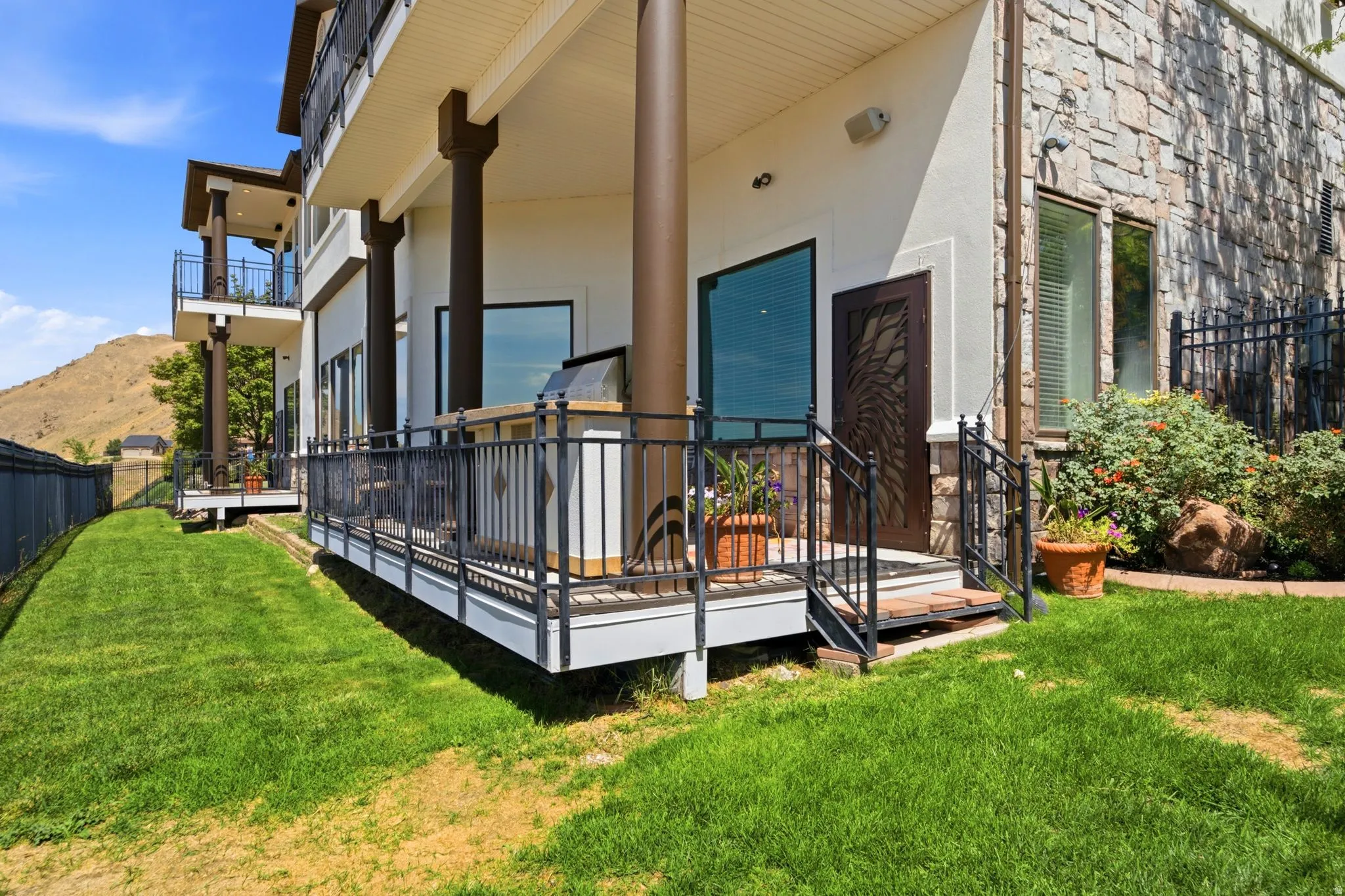 Expansive exterior deck featuring a built-in grill station, black metal railings, and direct yard access